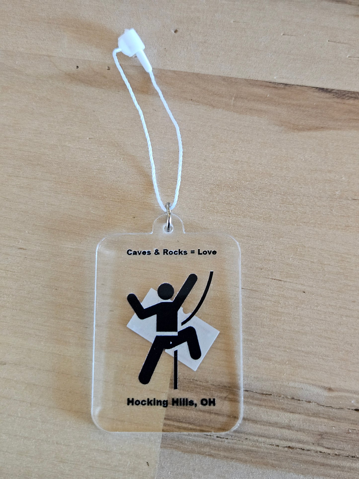 Clear plastic tag with black stick figure and text on a wooden surface