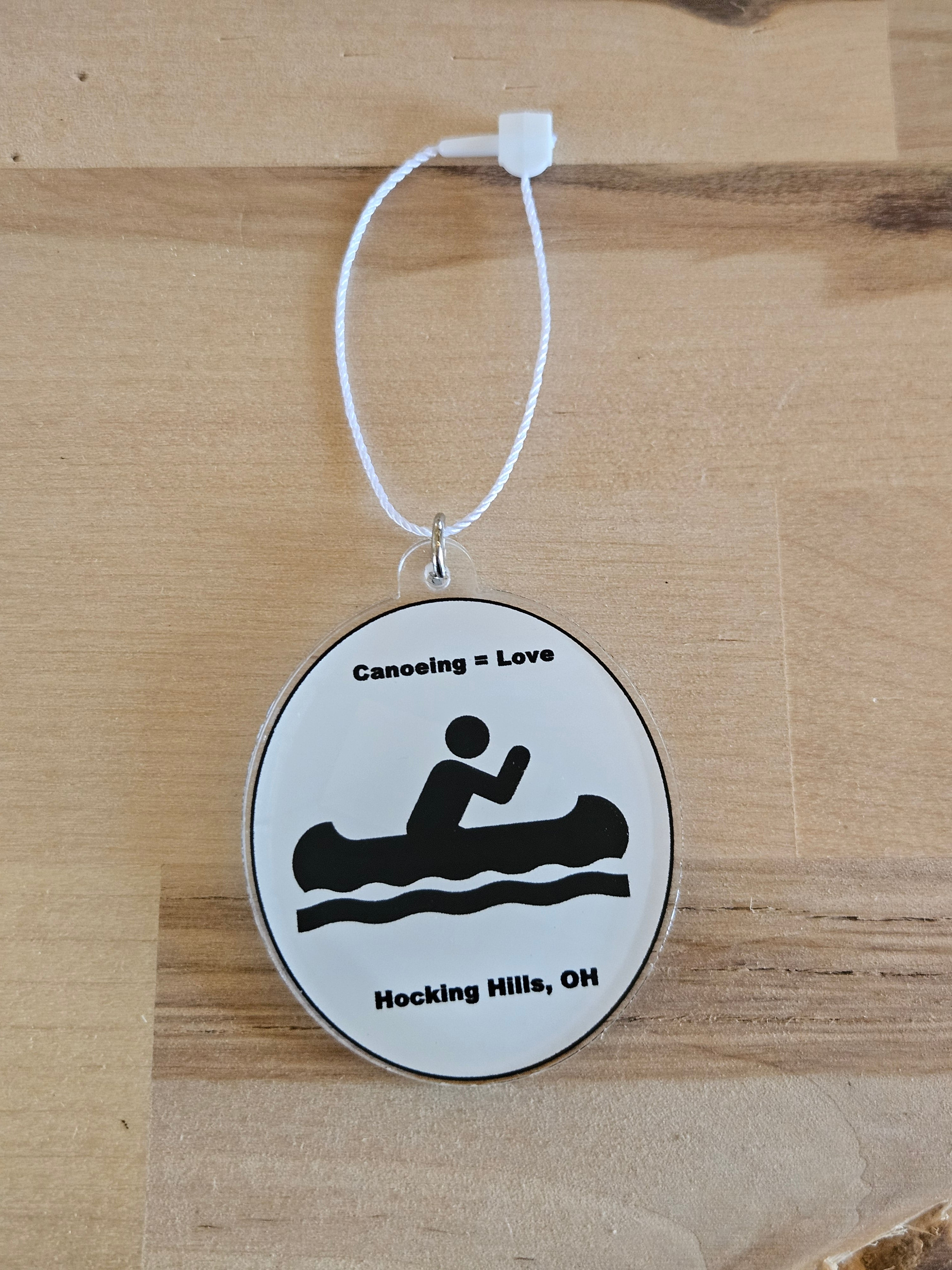 Round white tag with black silhouette and text on a wooden surface