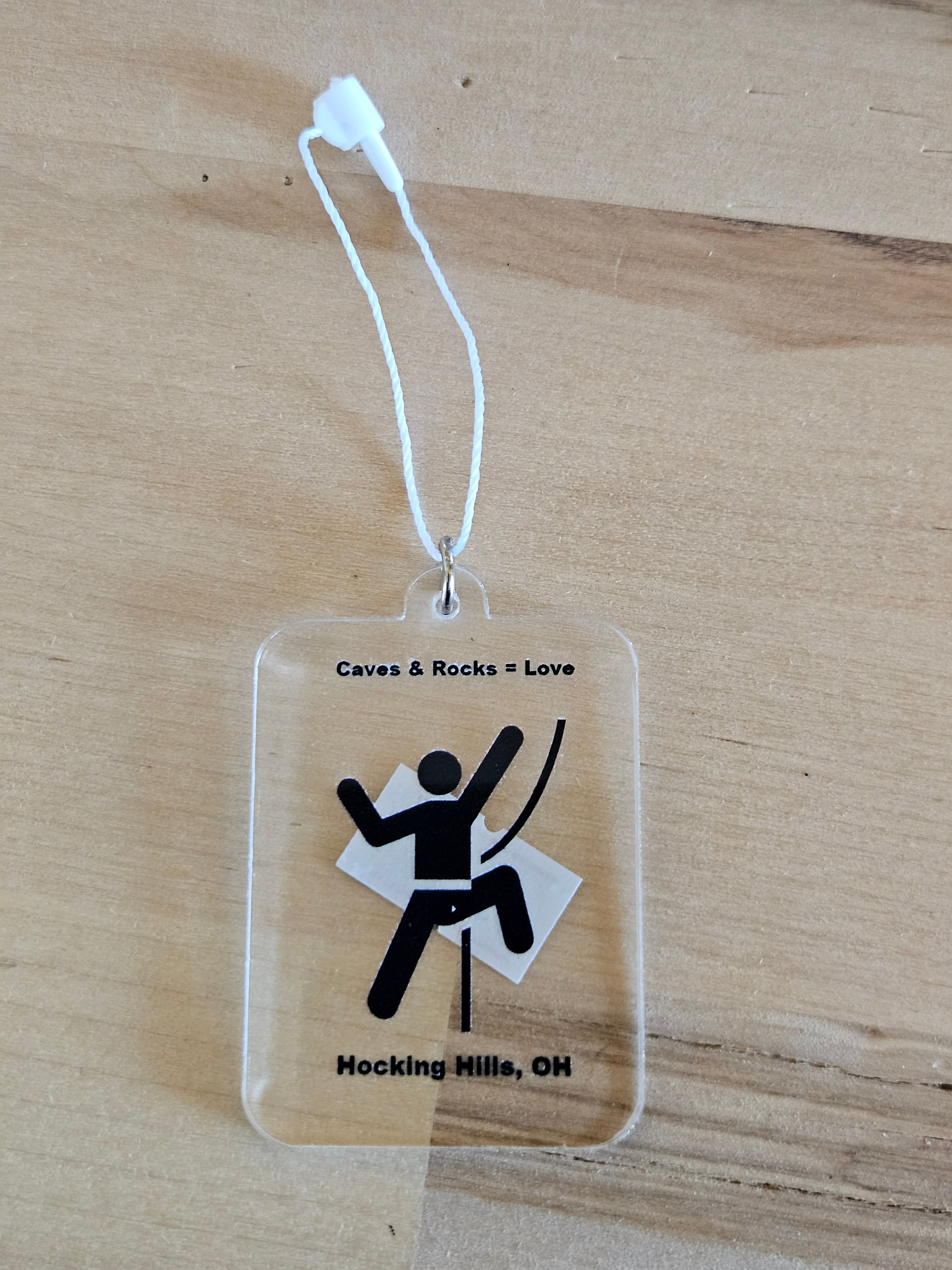 Clear plastic tag with black stick figure and text on a wooden surface