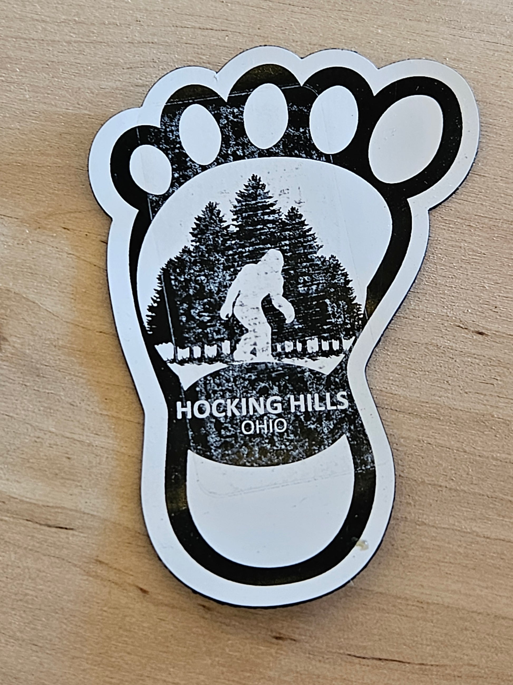 Sticker of a foot with a map of Hocking Hills, Ohio, on a wooden surface