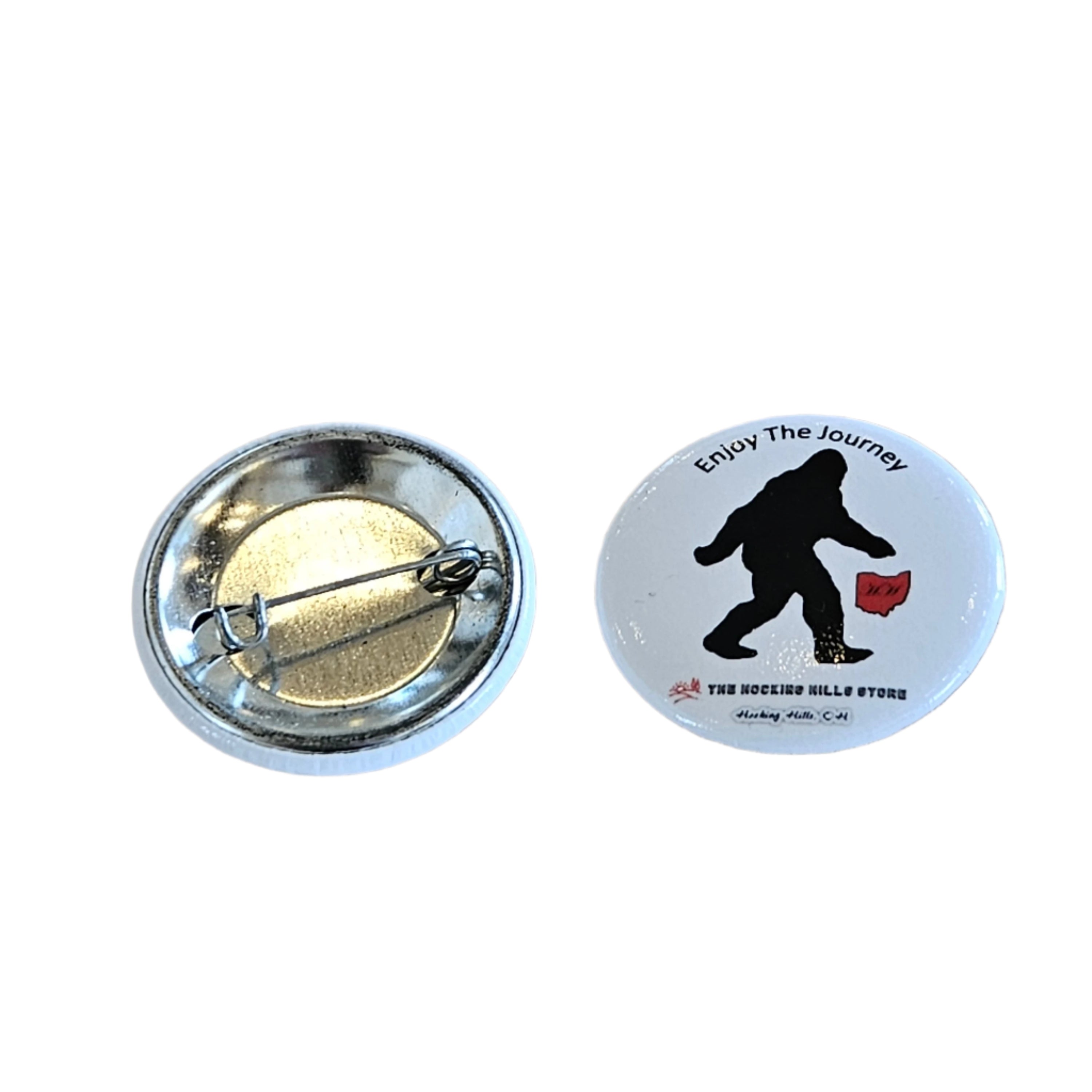 Button on a wooden surface, one with a silhouette design and the other metallic.