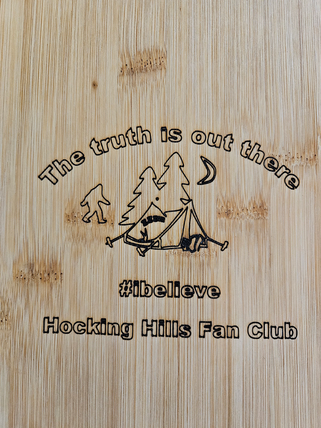 Wooden plaque with engraved text and logo on a bamboo background