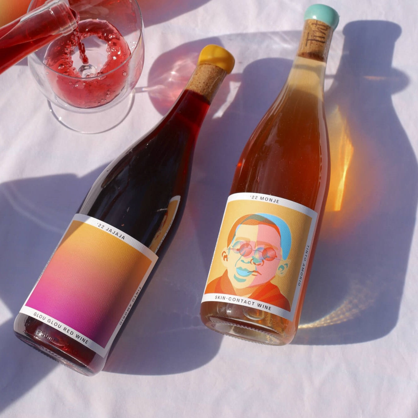 Two bottles of wine with colorful labels on a white surface.