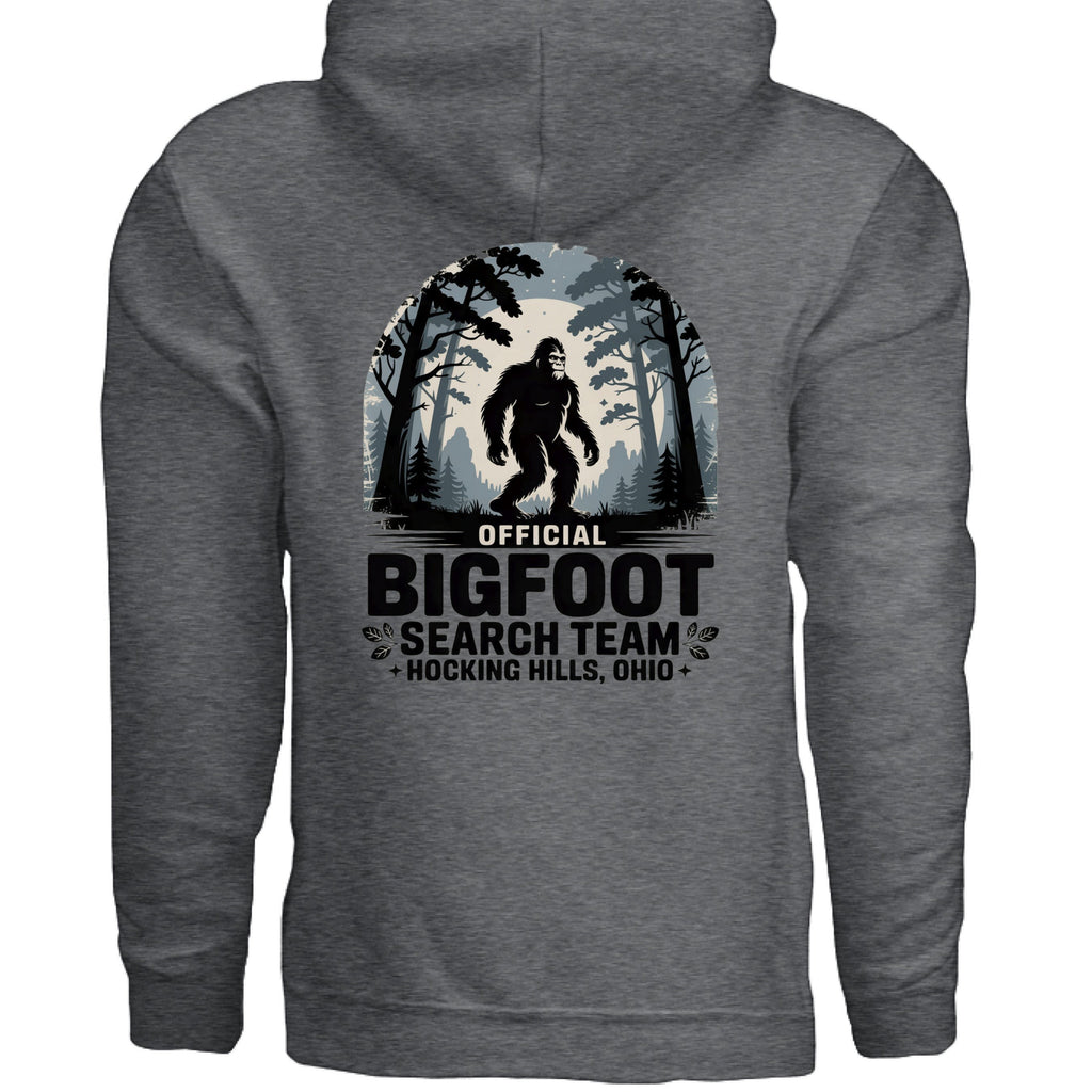 The Hocking Hills Store Official Bigfoot Search Team Hoodie features a Bigfoot graphic in a forest setting with text. This grey, cotton-polyester blend hoodie is perfect for cryptid enthusiasts.