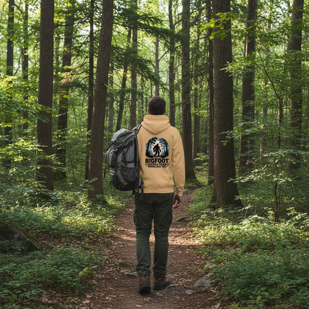 The Hocking Hills Store Official Bigfoot Search Team hoodie in tan, featuring a Bigfoot graphic in a forest setting with text.