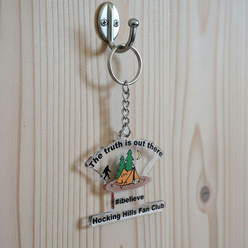 The Hocking Hills Store keychain with Bigfoot, tent, trees, and moon graphic. Features text 'The truth is out there #ibelieve Hocking Hills Fan Club'.