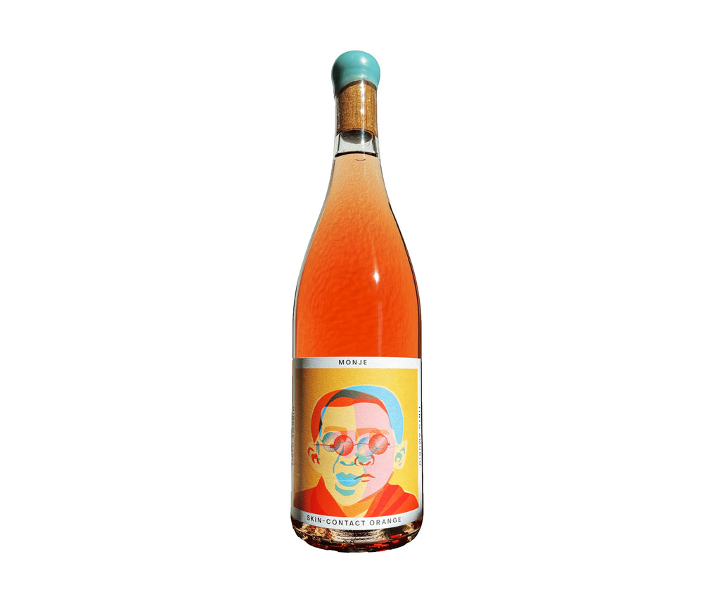 The Hocking Hills Store Monje 7-day skin-contact orange wine in a clear bottle with a colorful label featuring a portrait and a turquoise cap.