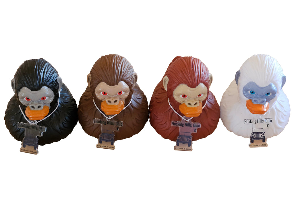 Four monkey-themed figurines with different color schemes on a wooden surface.