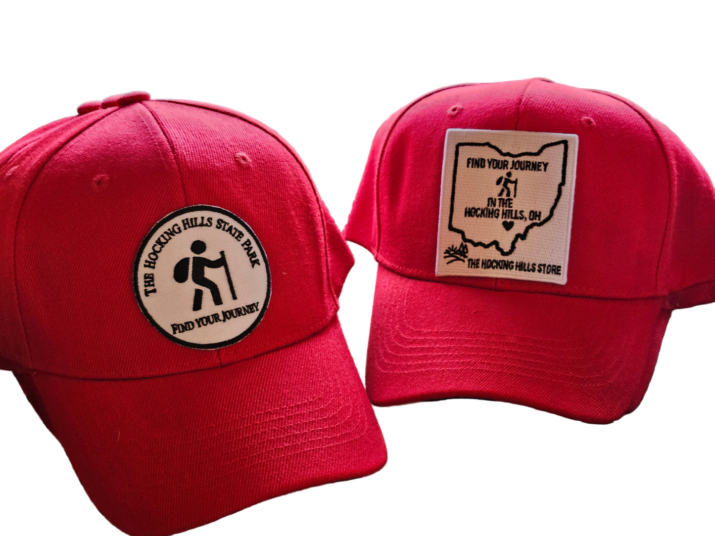 Two red hats with hiking-themed patches on a wooden surface.