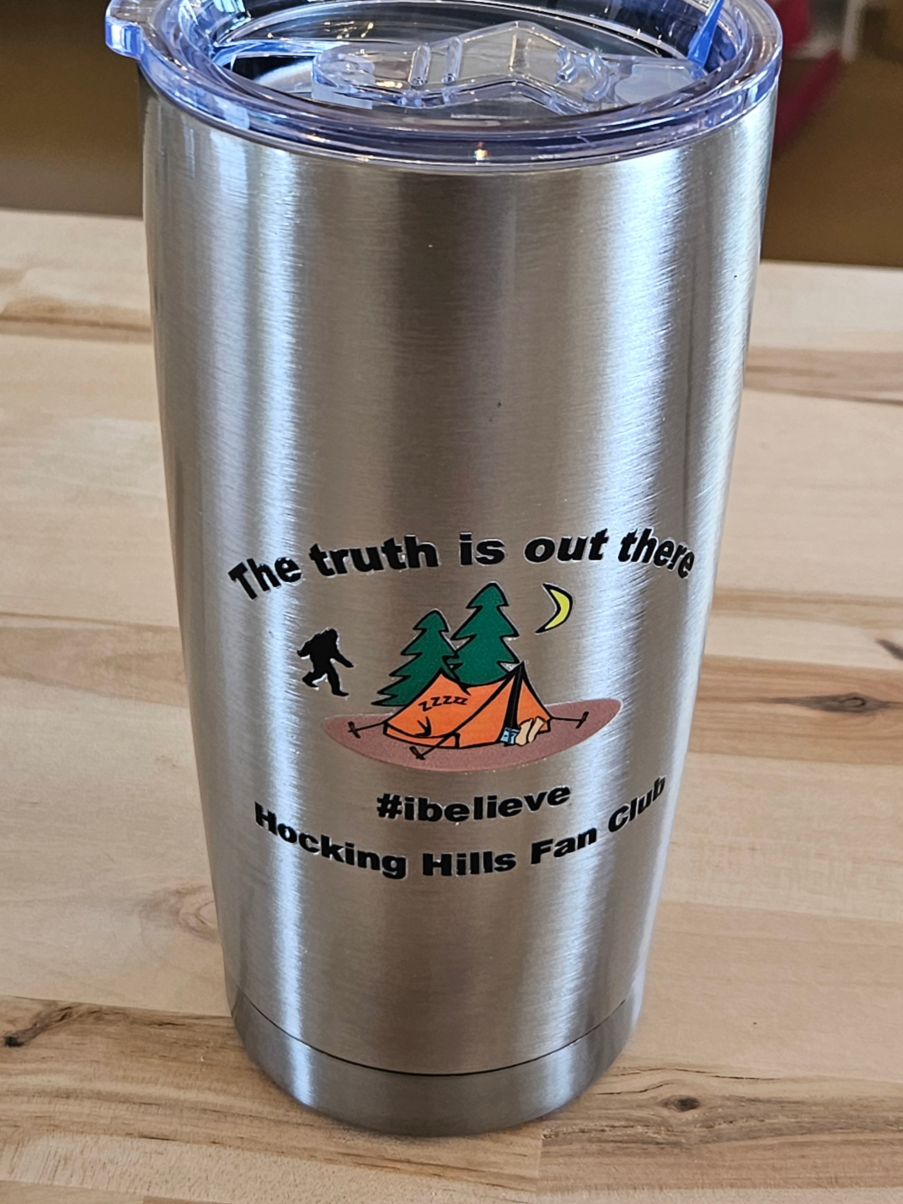 The Hocking Hills Store 20 oz stainless steel tumbler with Bigfoot, tent, trees, and moon graphic. "The truth is out there #ibelieve Hocking Hills Fan Club" text.