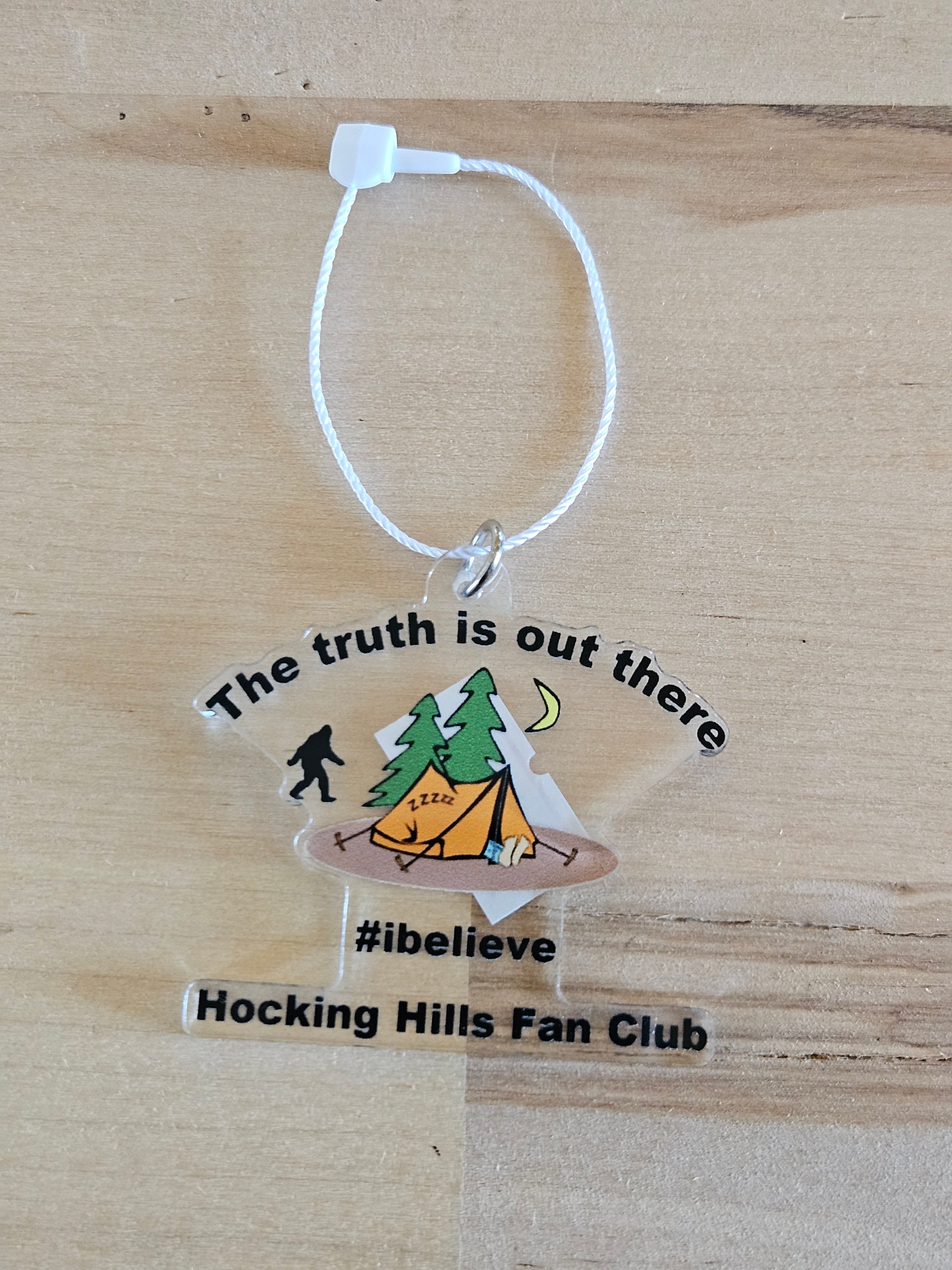 The Hocking Hills Store clear acrylic ornament with Bigfoot, tent, trees, moon, and text "The truth is out there #ibelieve Hocking Hills Fan Club".