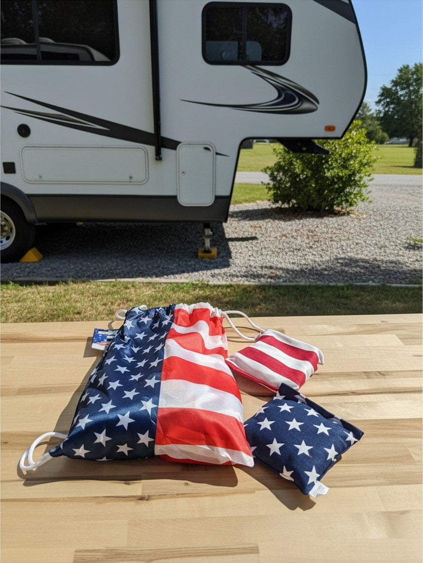 The Hocking Hills Store corn-hole bag set featuring American flag patterns on a wooden table outdoors.