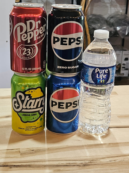 The Hocking Hills Store selection of assorted soda cans and a bottle of Pure Life water on a wooden surface.
