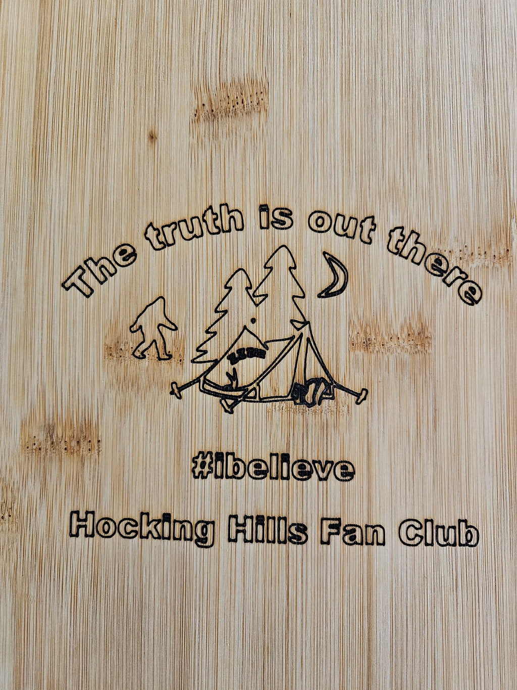 The Hocking Hills Store bamboo cutting board with Bigfoot, tent, trees, moon, and text "The truth is out there #ibelieve Hocking Hills Fan Club".