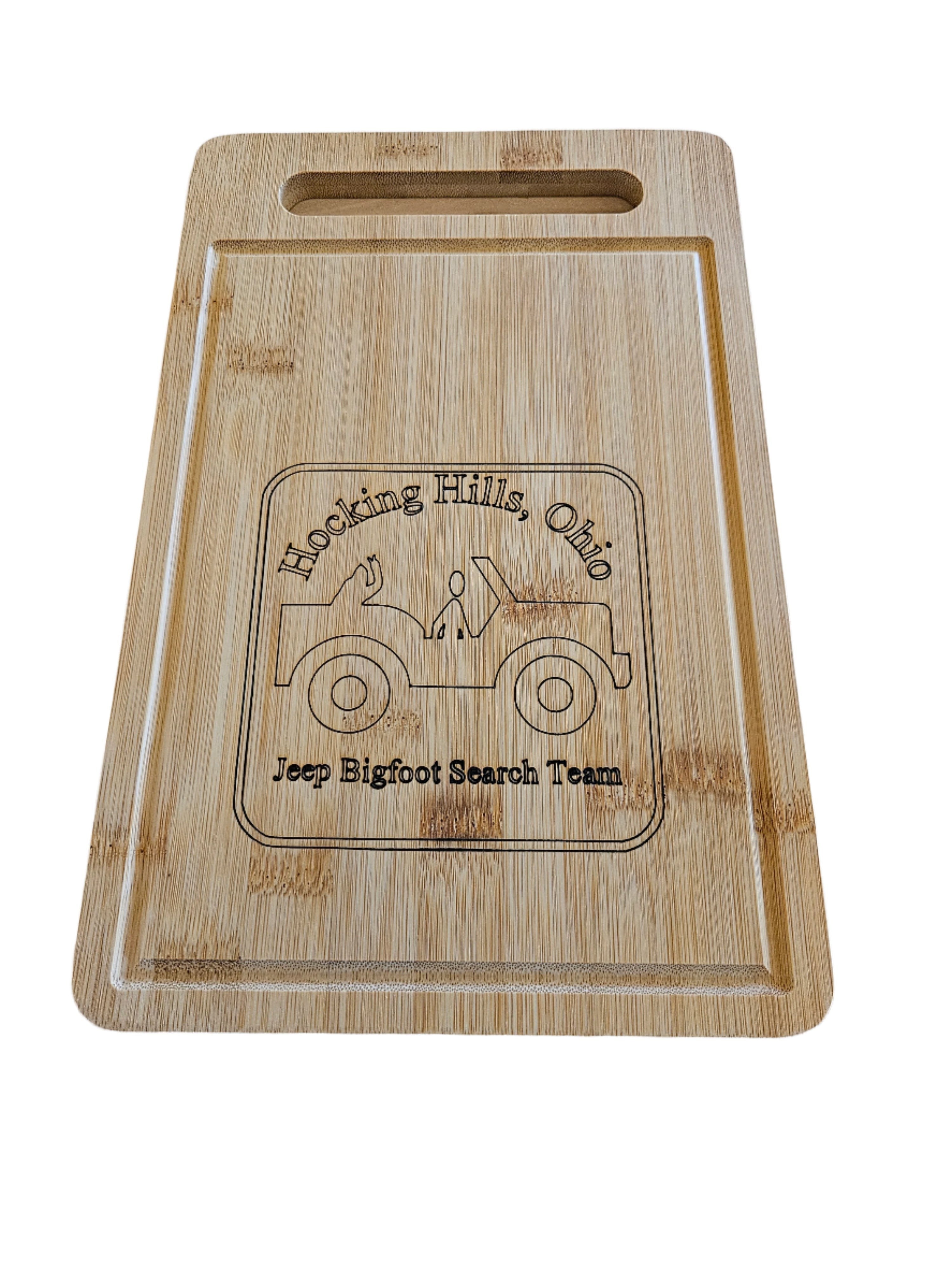 The Hocking Hills Store Rectangle bamboo cutting board with a carved Jeep and Bigfoot theme. Features a juice groove and handle.
