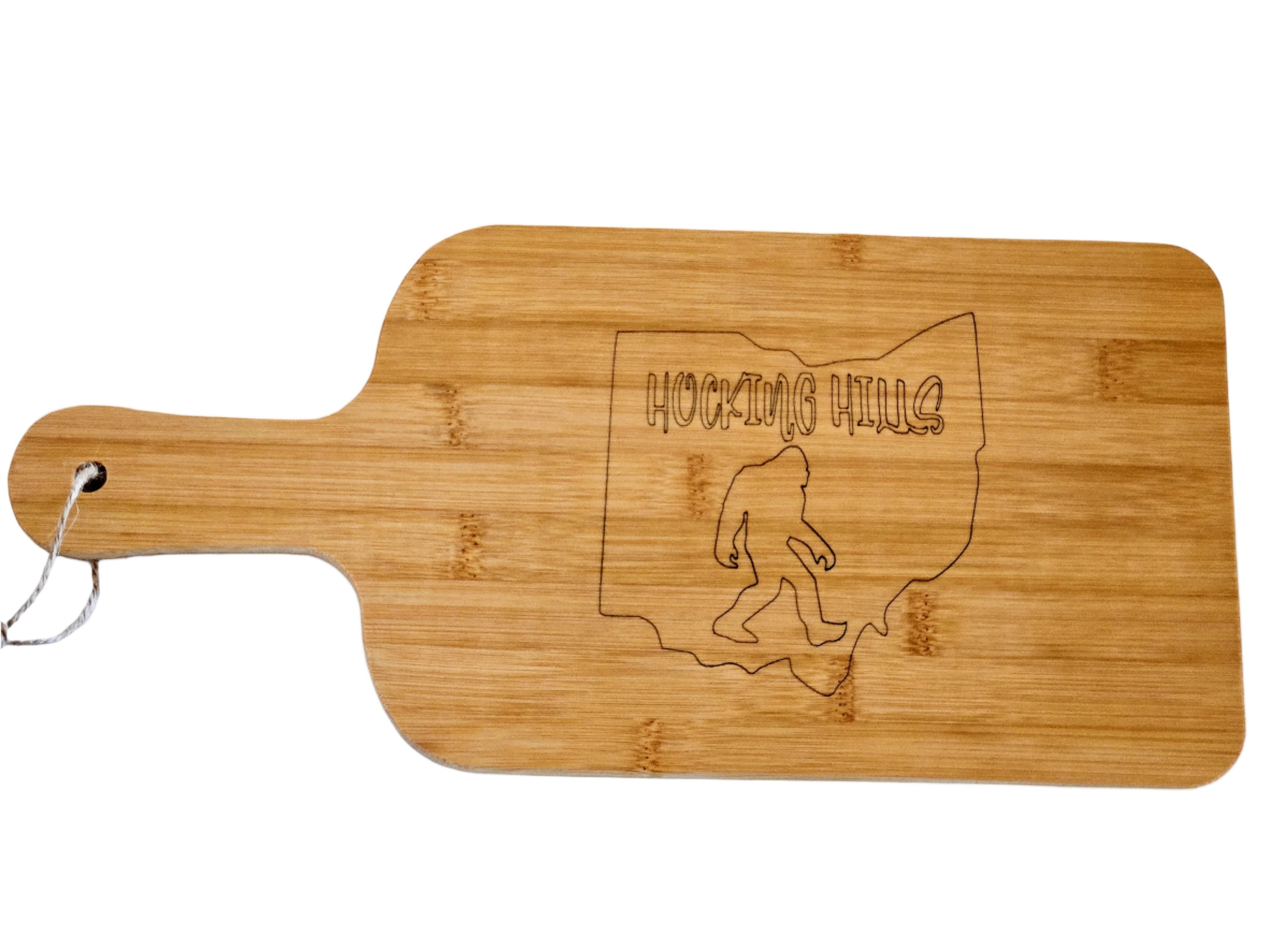 The Hocking Hills Store bamboo cutting board with Ohio outline and Bigfoot engraving. Features a handle and hanging loop.