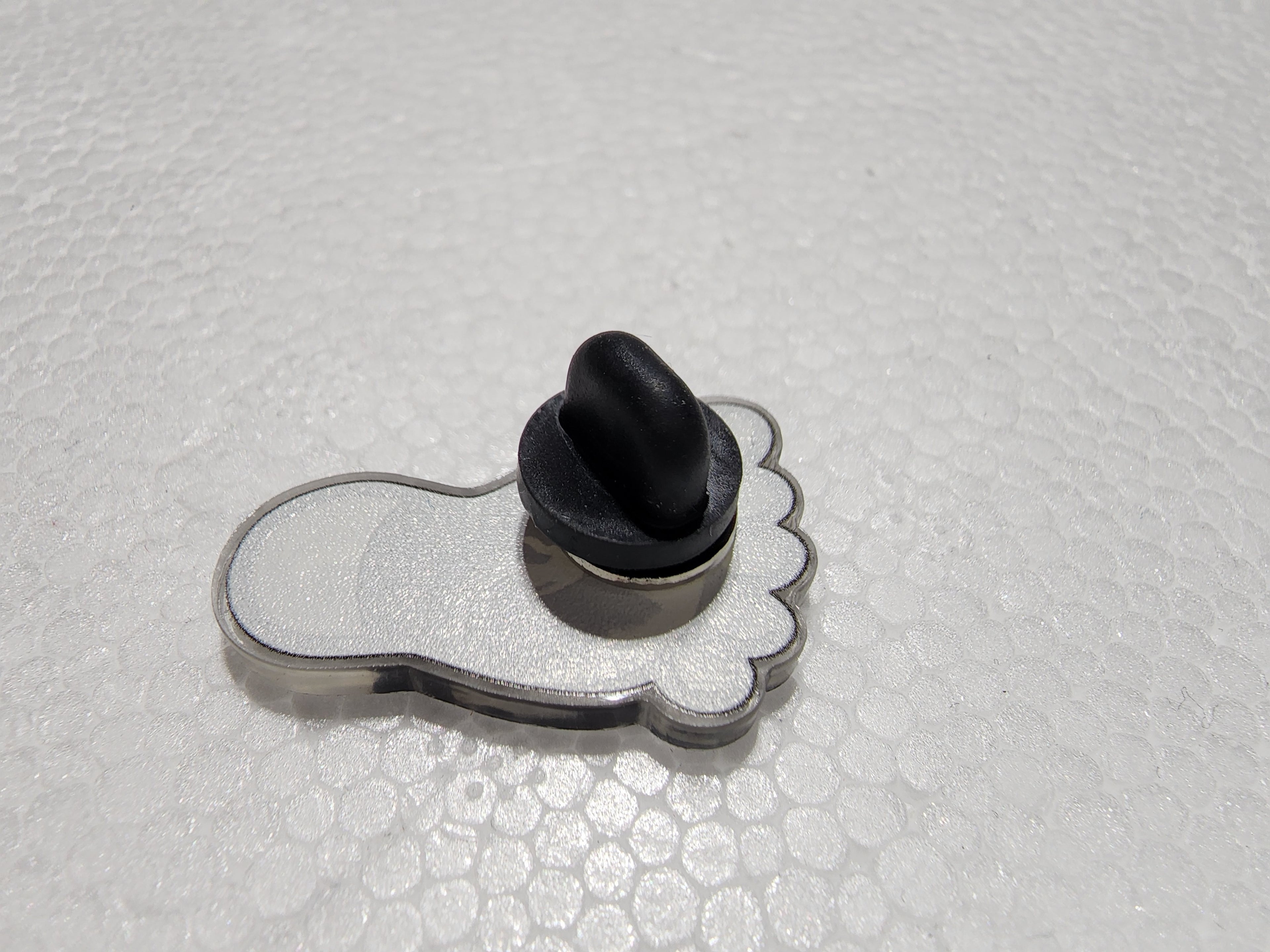 The Hocking Hills Store Bigfoot Hocking Hills enamel pin shaped like a footprint with a black backing pin.