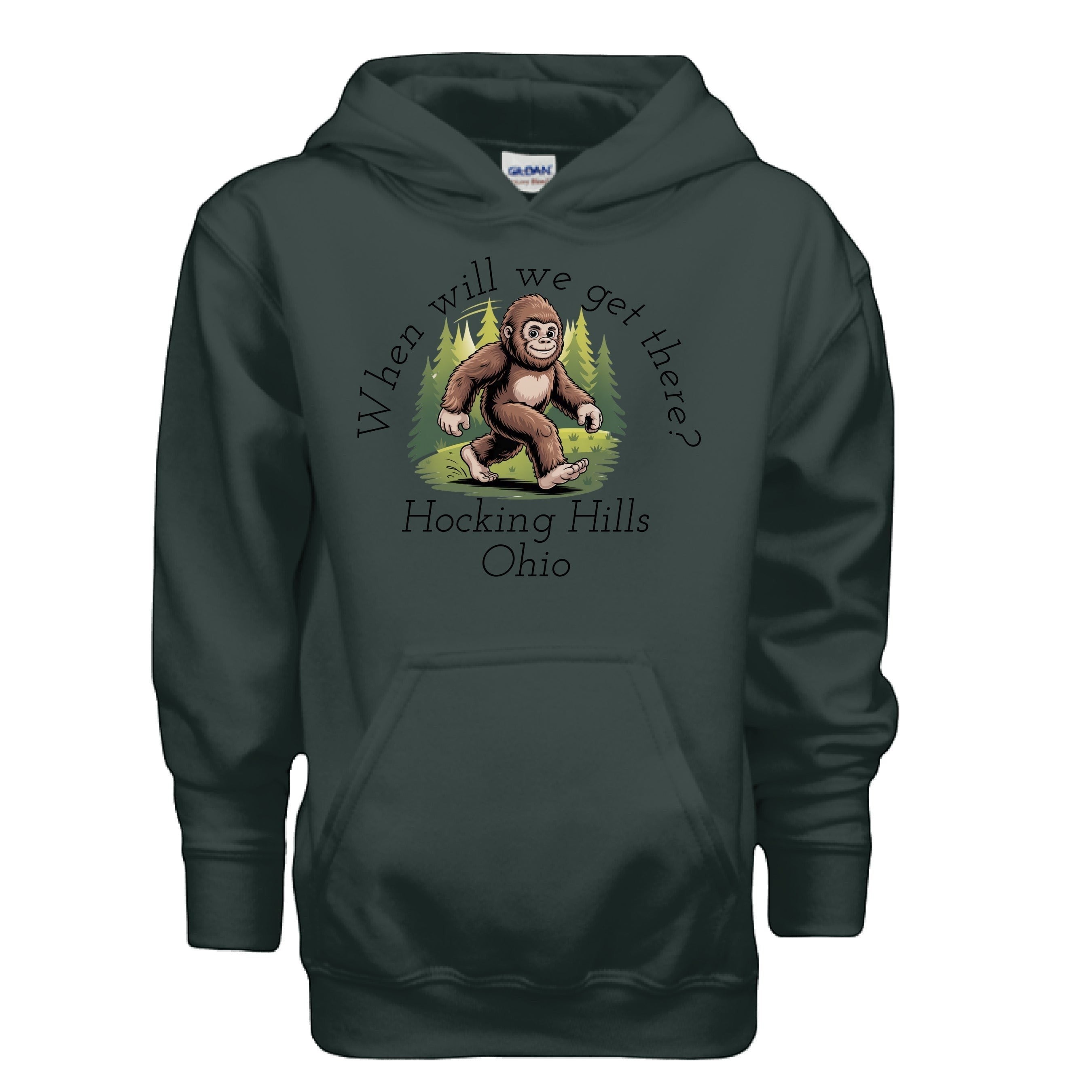 The Hocking Hills Store dark green youth Bigfoot hoodie with a graphic of Bigfoot walking through trees and the text "When Will We Get There? Hocking Hills Ohio."