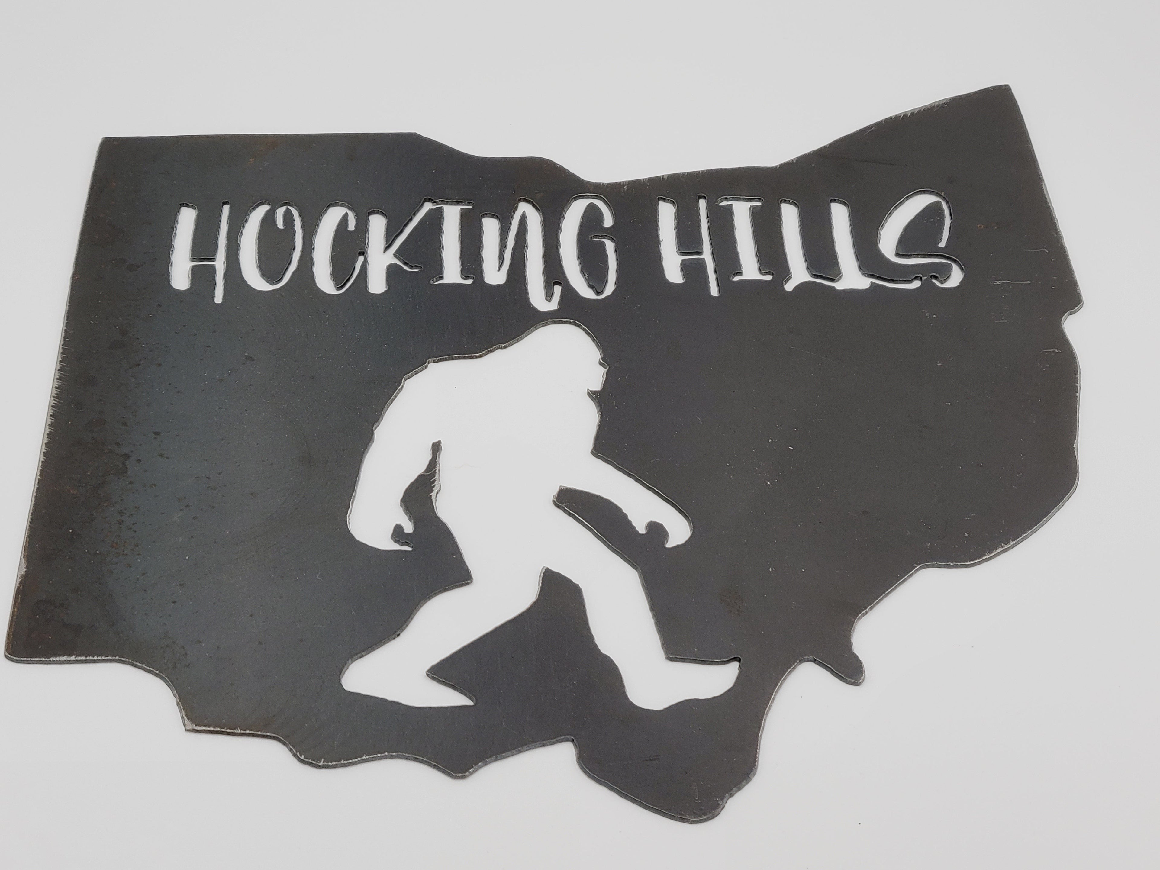 The Hocking Hills Store Bigfoot metal art sign shaped like Ohio with 'HOCKING HILLS' text.