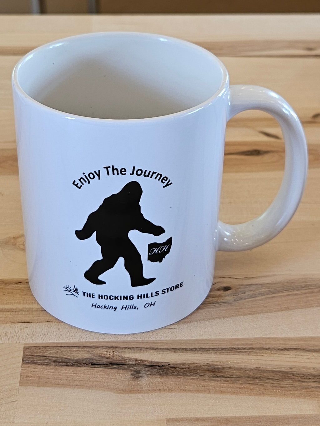 The Hocking Hills Store white ceramic mug with black Bigfoot silhouette and "Enjoy The Journey" text.