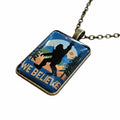 The Hocking Hills Store Bigfoot We Believe pendant features a silhouette of Bigfoot against a sunset and forest scene. Bronze chain.