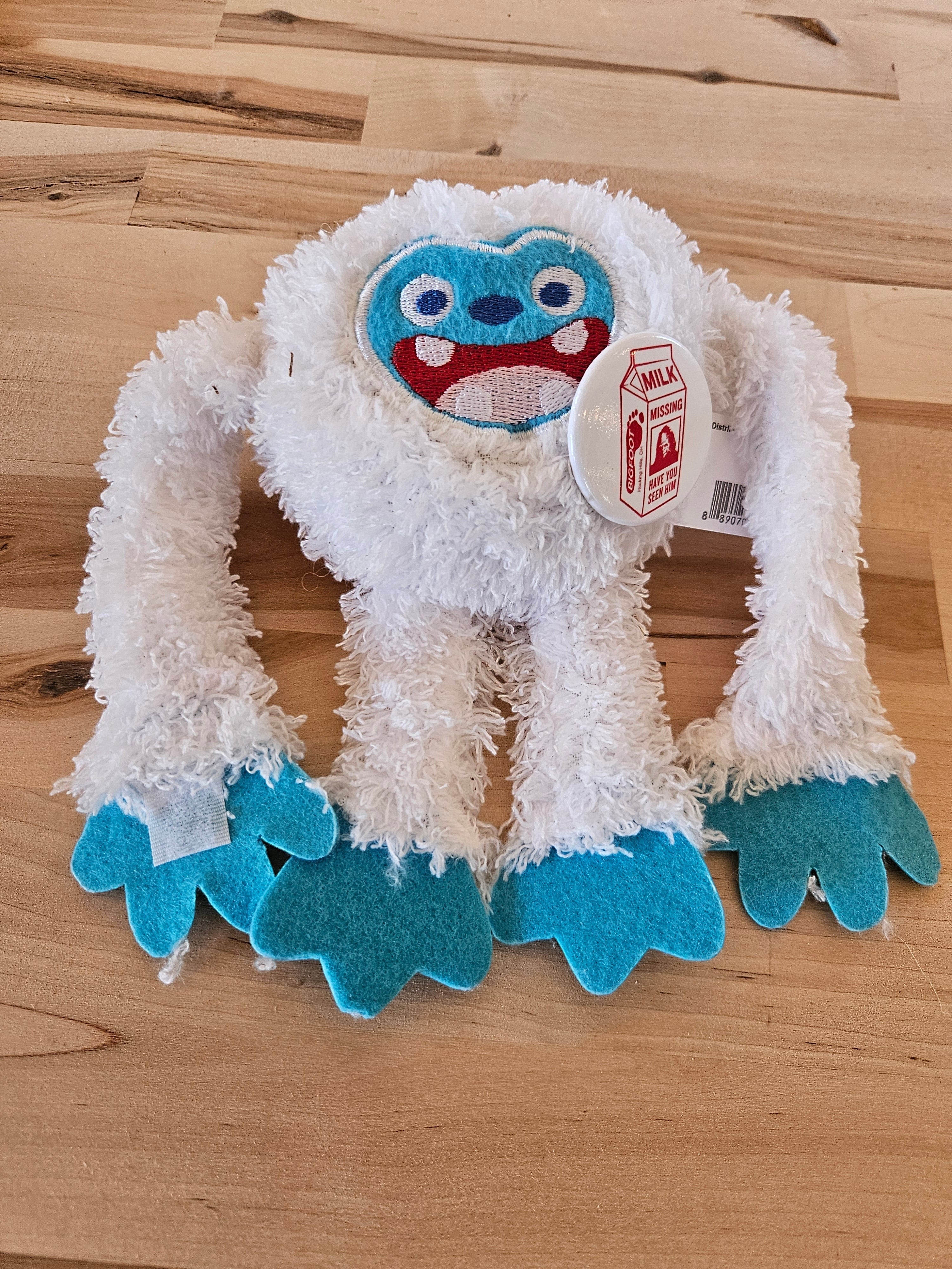 The Hocking Hills Store white plush Bigfoot with blue face and feet, fuzzy texture, and a "Milk Missing" tag.