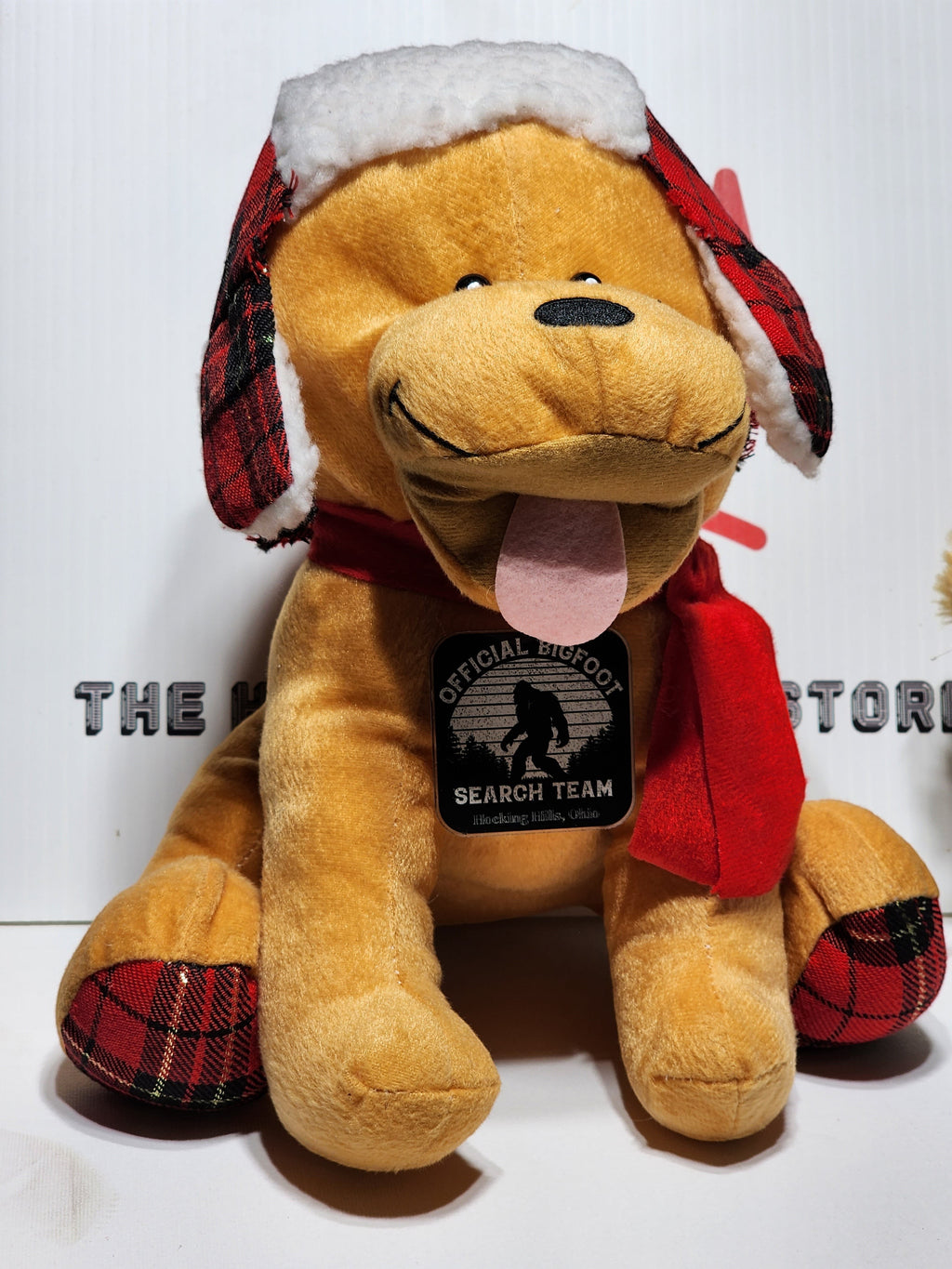 The Hocking Hills Store Bigfoot Search Team stuffed puppy with red scarf, hat, and plaid accents.