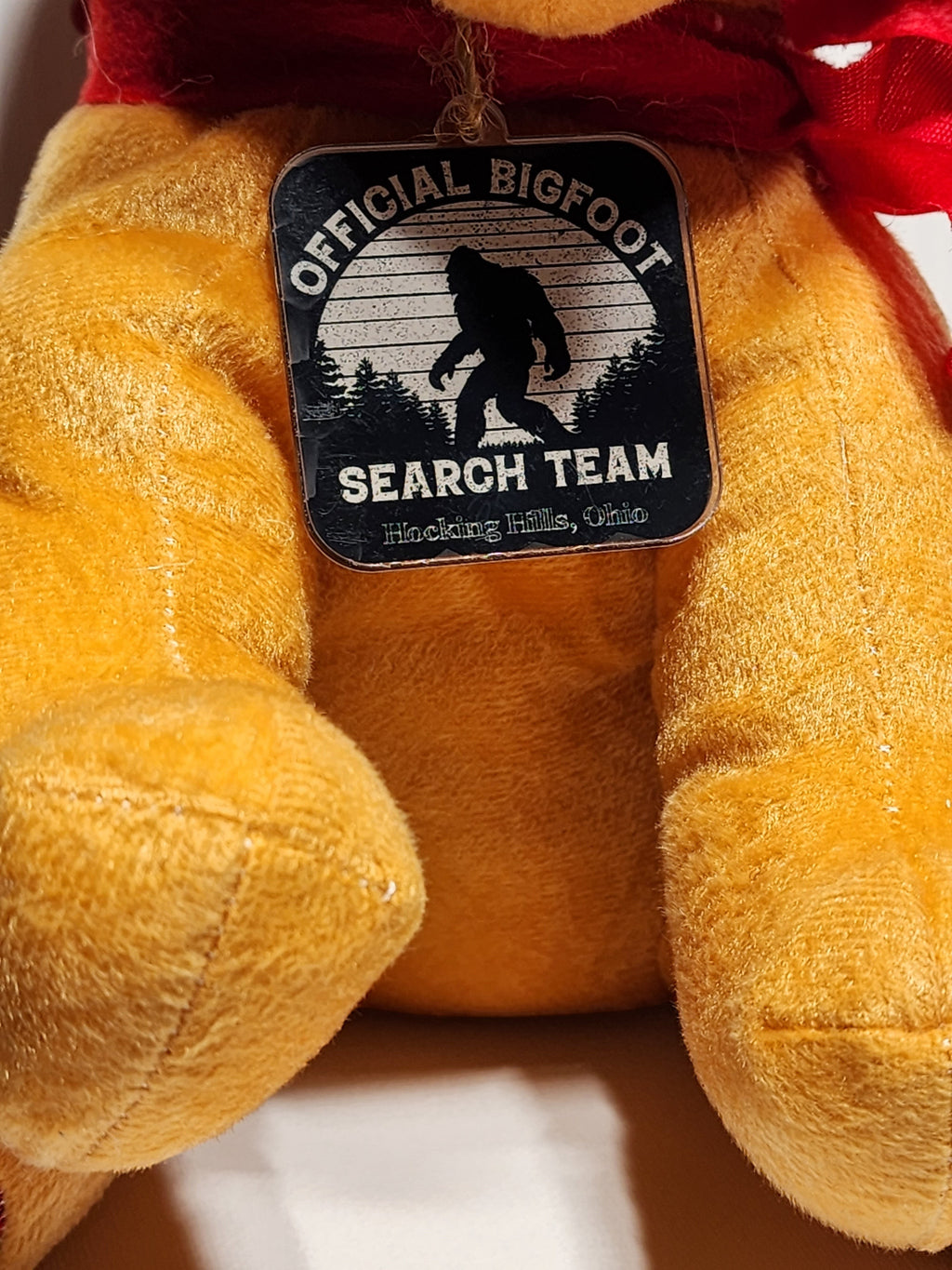 The Hocking Hills Store Bigfoot Search Team stuffed puppy in yellow plush with red scarf, hat, and tie.
