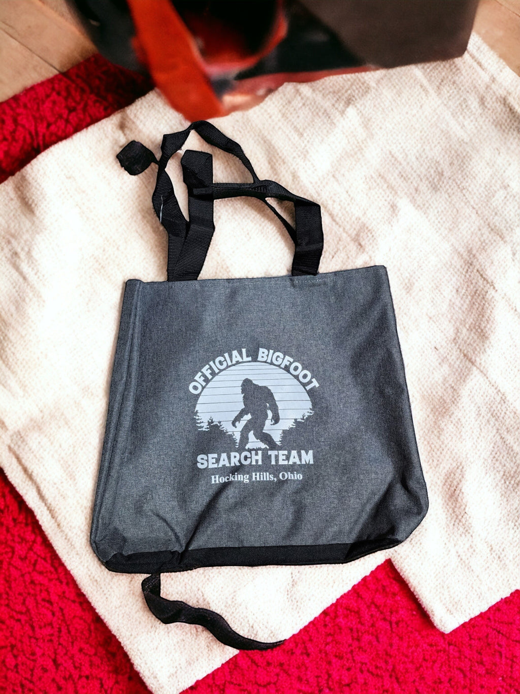 The Hocking Hills Store Official Bigfoot Search Team tote bag in dark grey with black handles and a Bigfoot graphic.