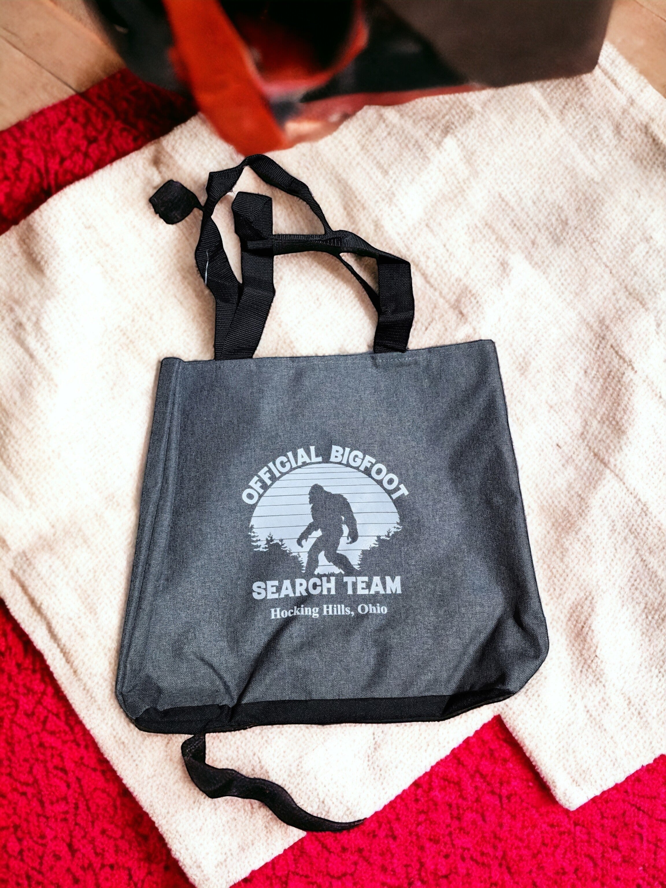 The Hocking Hills Store Official Bigfoot Search Team tote bag in dark grey with black handles and a Bigfoot graphic.
