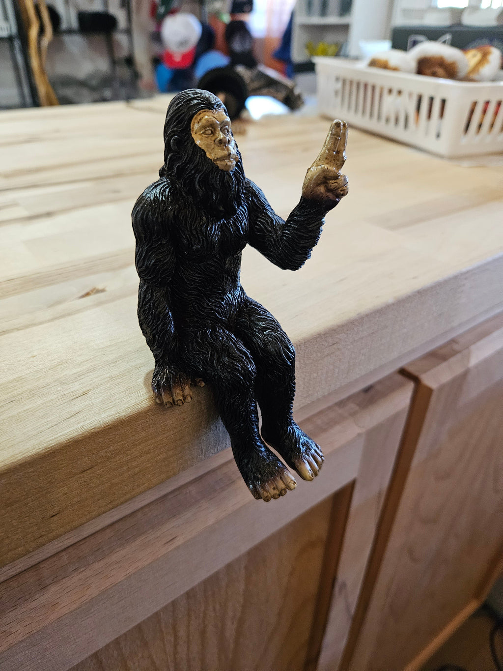 The Hocking Hills Store Bigfoot shelf sitting statue is black metal with a gold face and hands, sitting on a wooden surface.