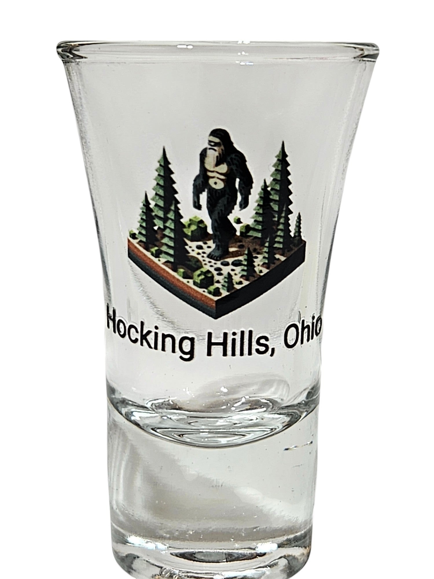 The Hocking Hills Store Bigfoot shot glass features a Bigfoot figure in a forest scene with text 'Hocking Hills, Ohio'.