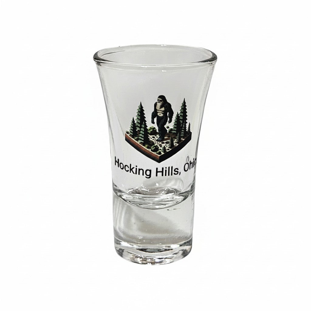 The Hocking Hills Store Bigfoot shot glass with a forest scene and Bigfoot graphic. Text reads Hocking Hills, Ohio.