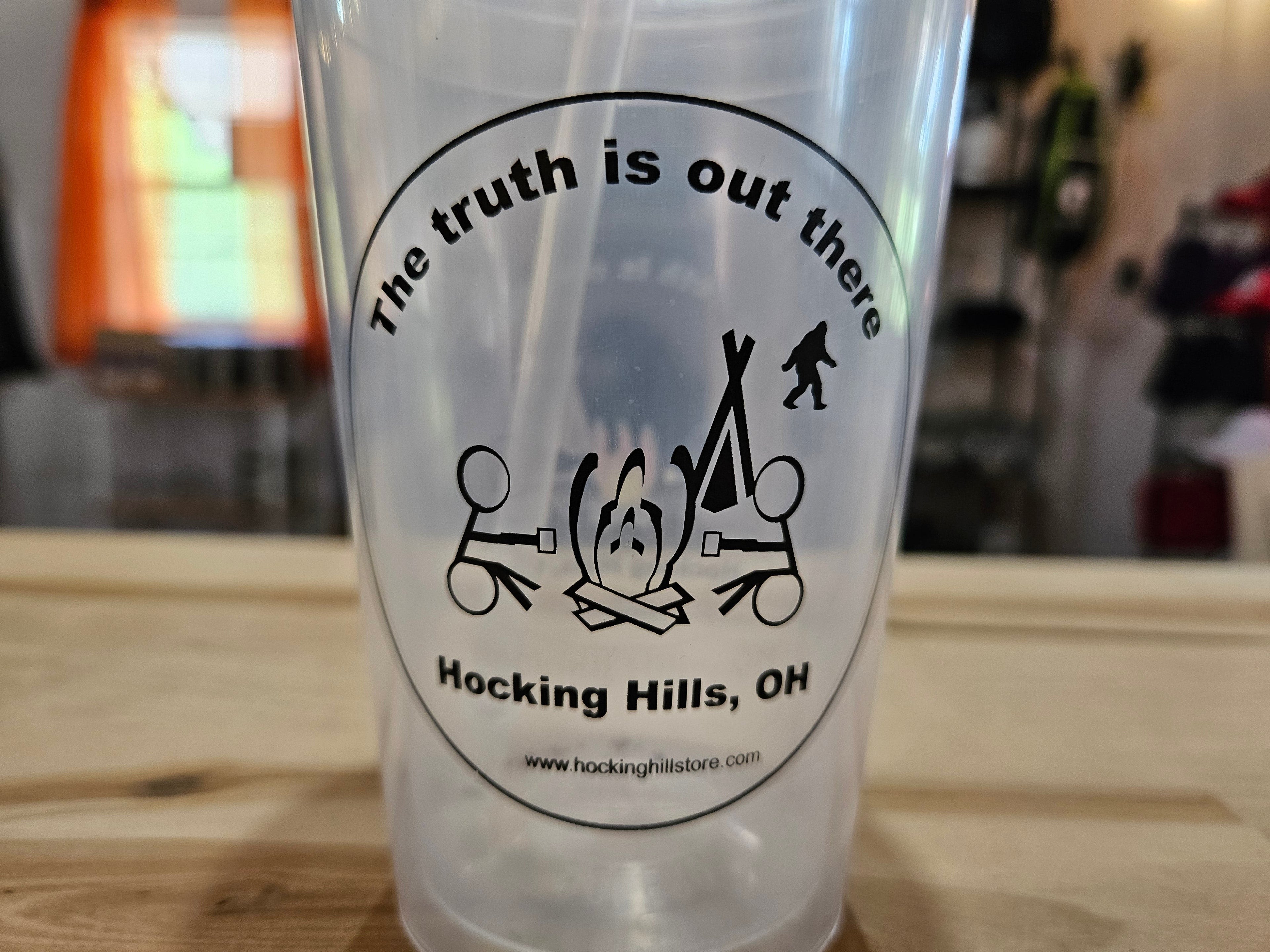 The Hocking Hills Store clear plastic sipper cup with Bigfoot and campfire graphic. Features "The Truth is out there" text.