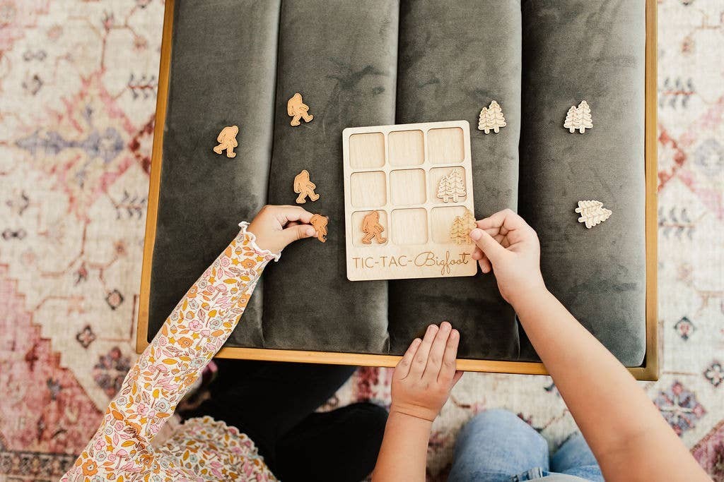 The Hocking Hills Store Bigfoot Tic-Tac-Toe game made of maple and cherry wood, featuring Bigfoot and pine tree playing pieces.