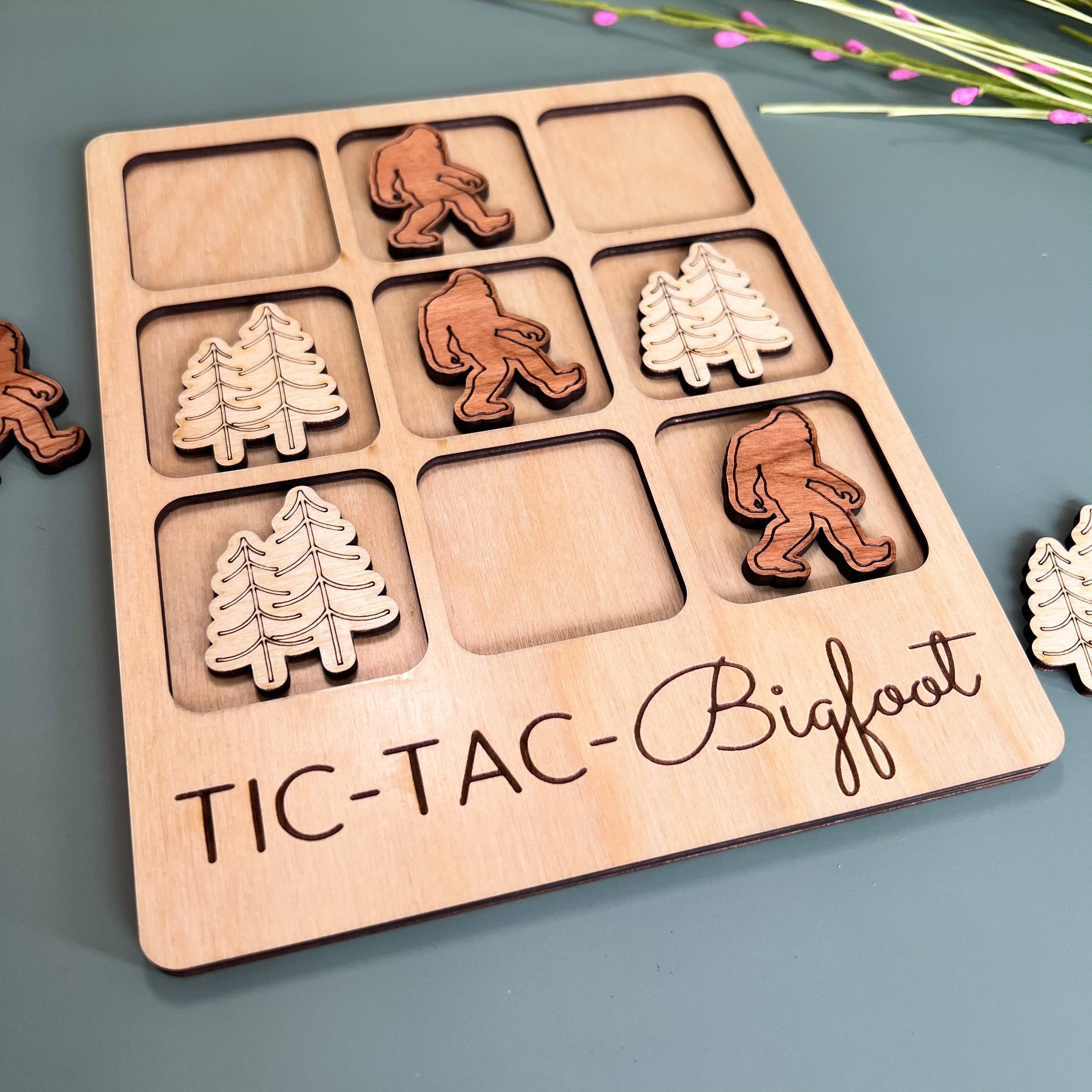 The Hocking Hills Store Bigfoot Tic-Tac-Toe game made of maple and cherry wood. Features Bigfoot and pine tree playing pieces.
