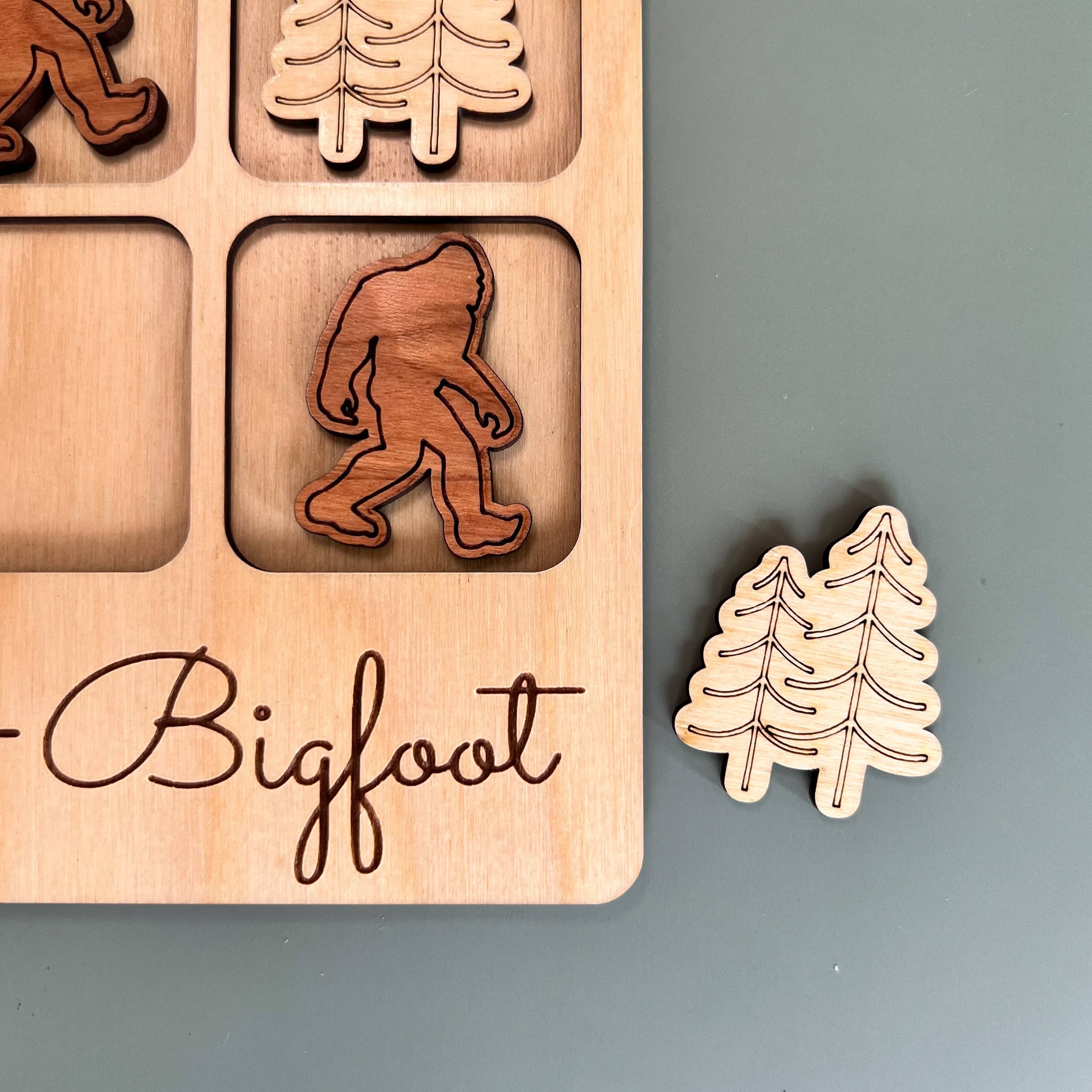 The Hocking Hills Store Bigfoot Tic-Tac-Toe game board made of maple wood with cherry and maple wood playing pieces.