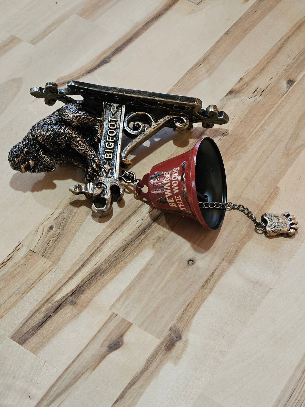 The Hocking Hills Store Bigfoot wall art and bell features a metal Bigfoot figure and a red bell with "Beware the Woods" text. Includes a Bigfoot foot pull chain.