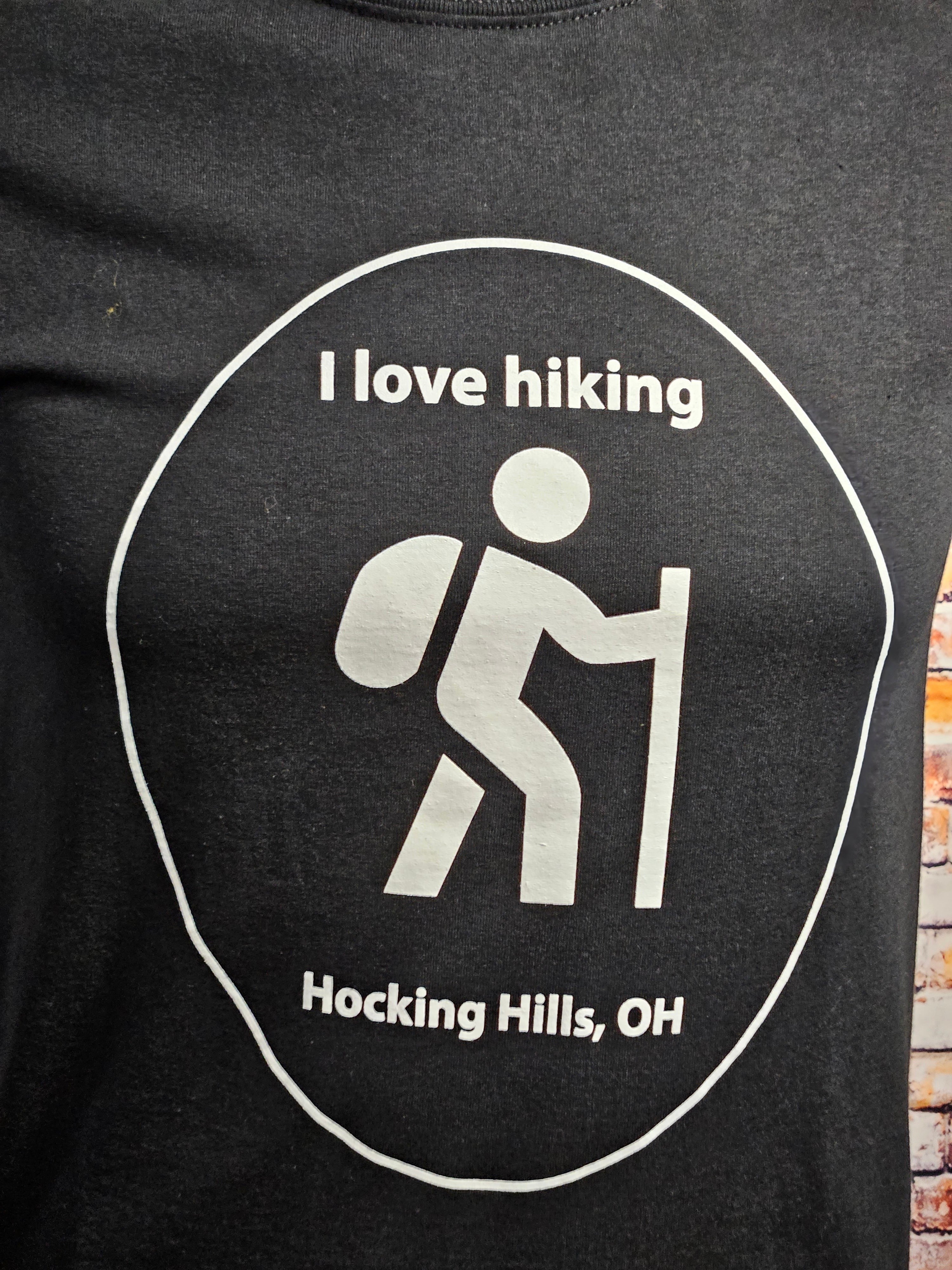 The Hocking Hills Store black cotton t-shirt with a white graphic that says "I love hiking" and depicts a hiker with a backpack and walking stick.