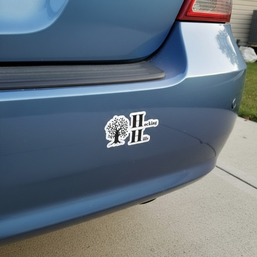 The Hocking Hills Store black and white bumper sticker with stylized tree and logo on a blue car bumper.
