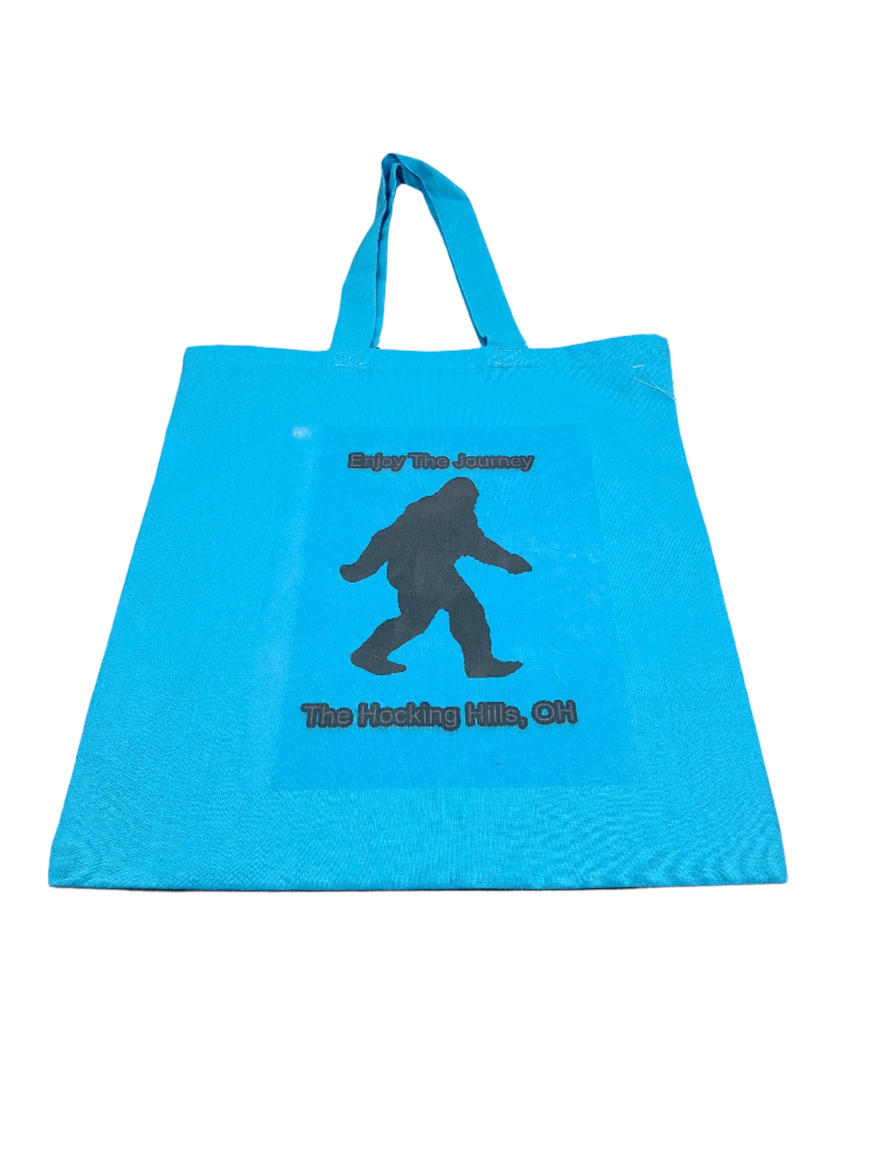 The Hocking Hills Store blue canvas tote bag with Bigfoot graphic and text "Enjoy The Journey The Hocking Hills, OH".