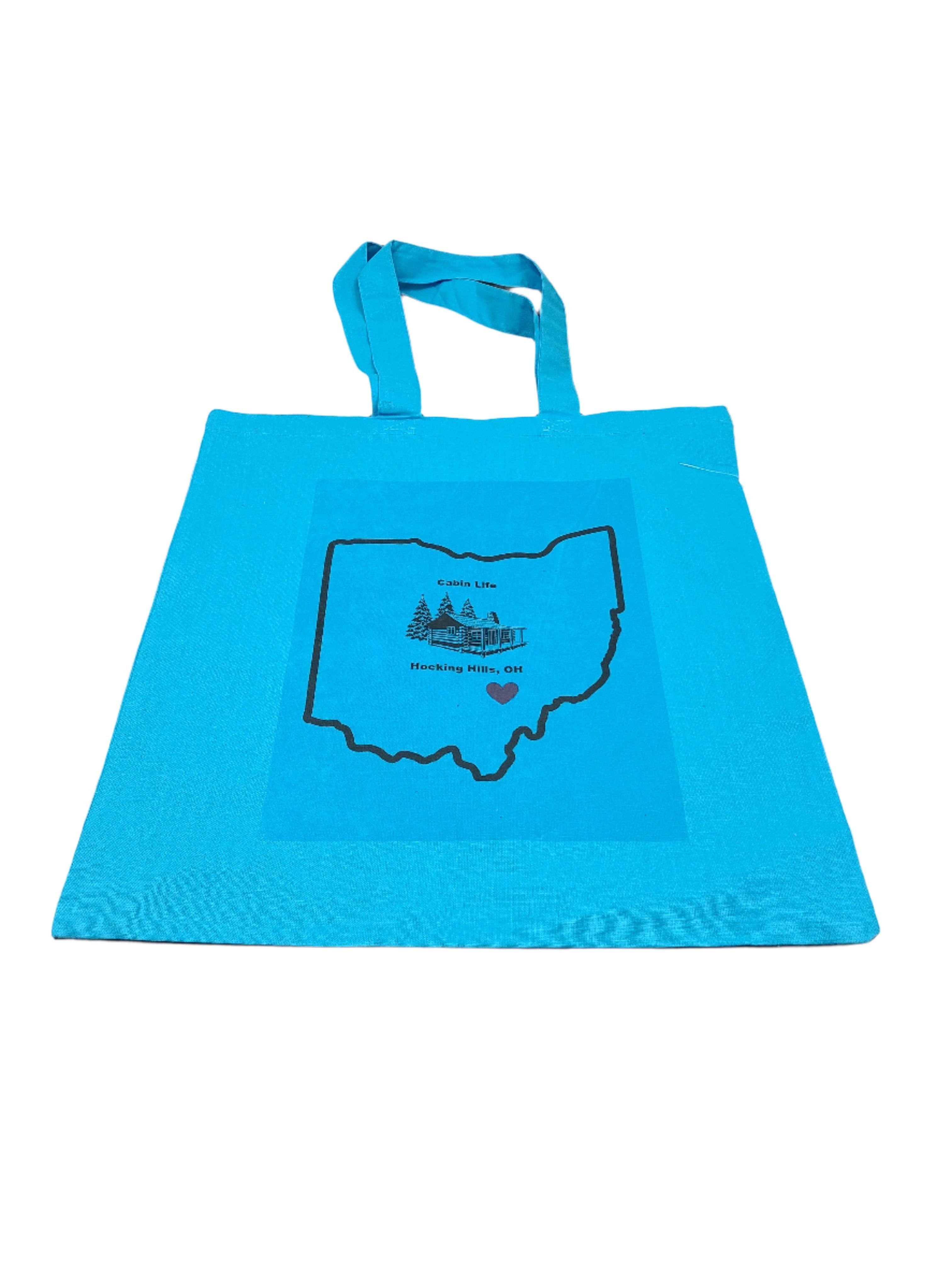 The Hocking Hills Store blue canvas tote bag with Ohio outline graphic and cabin illustration.