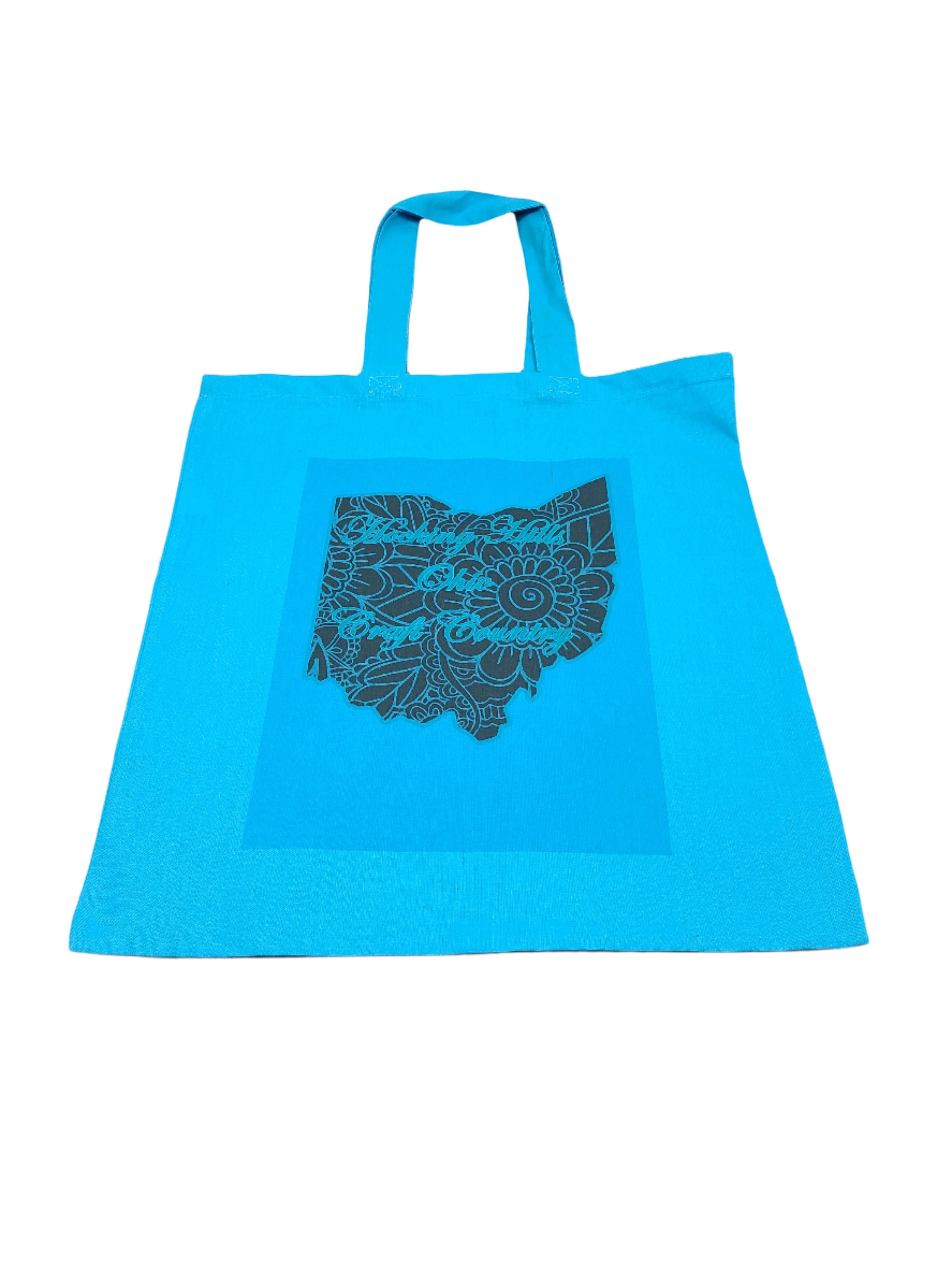 The Hocking Hills Store blue canvas tote bag with a dark grey Ohio map design featuring floral patterns.