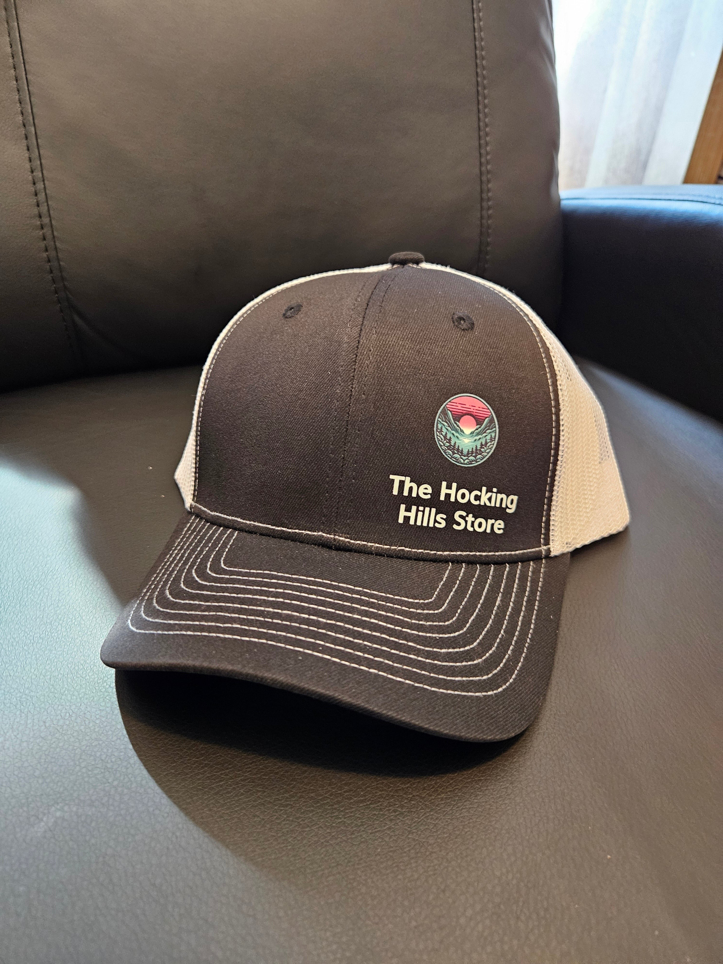 The Hocking Hills Store brown and white trucker hat with embroidered logo, adjustable back for a comfortable fit.
