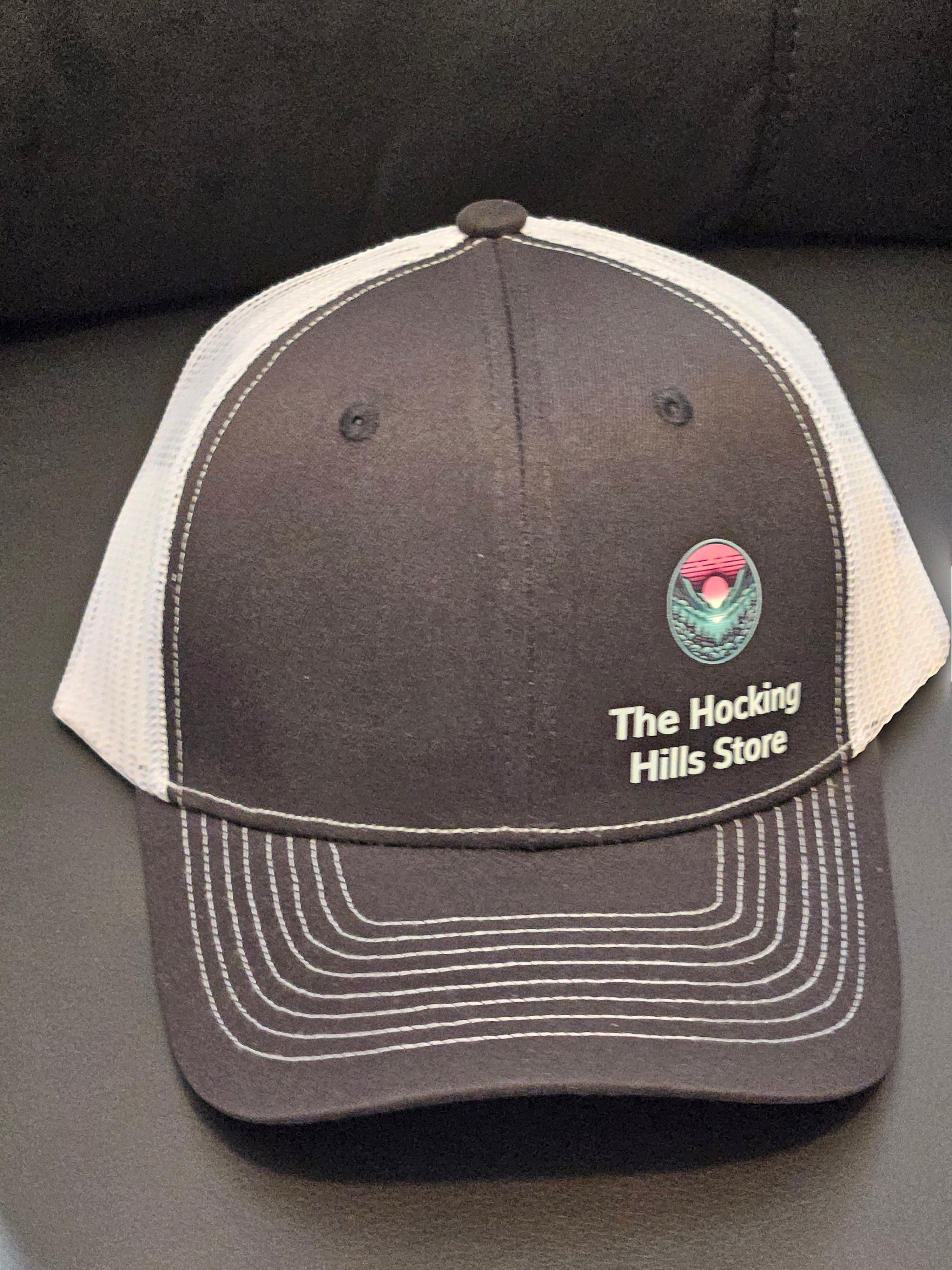 The Hocking Hills Store brown trucker hat with white mesh back and embroidered logo. Adjustable for a comfortable fit.