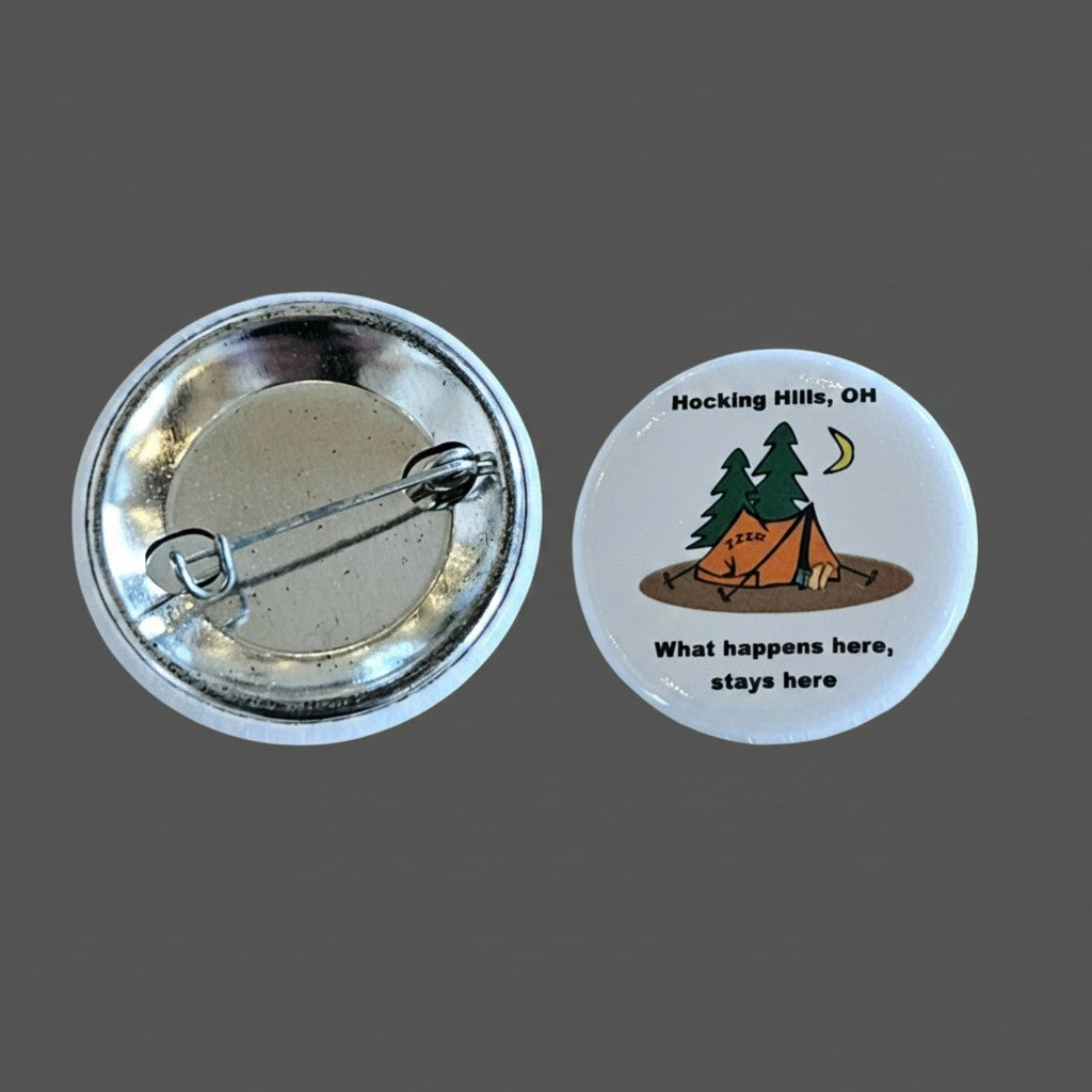 The Hocking Hills Store "What Happens Here Stays Here" button features a cartoon camping scene with a tent, trees, and moon. It has a pin backing.
