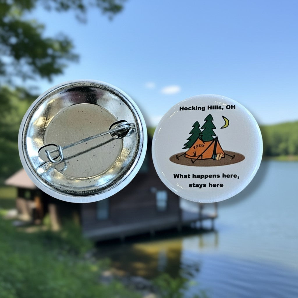 The Hocking Hills Store "What Happens Here Stays Here" button features a cartoon camping scene with a tent, trees, and moon. It has a pin backing.