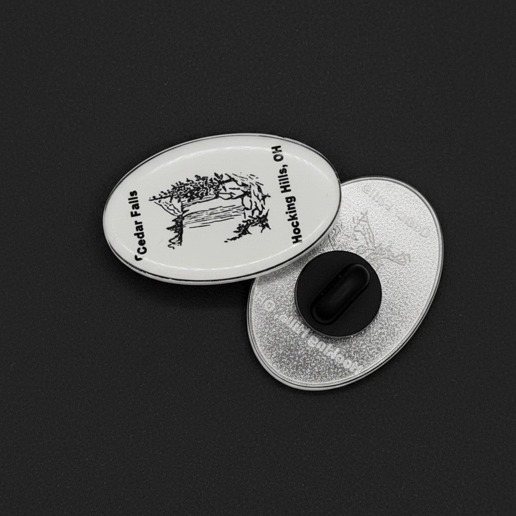 The Hocking Hills Store oval enamel pin featuring a black and white illustration of Cedar Falls waterfall and text.