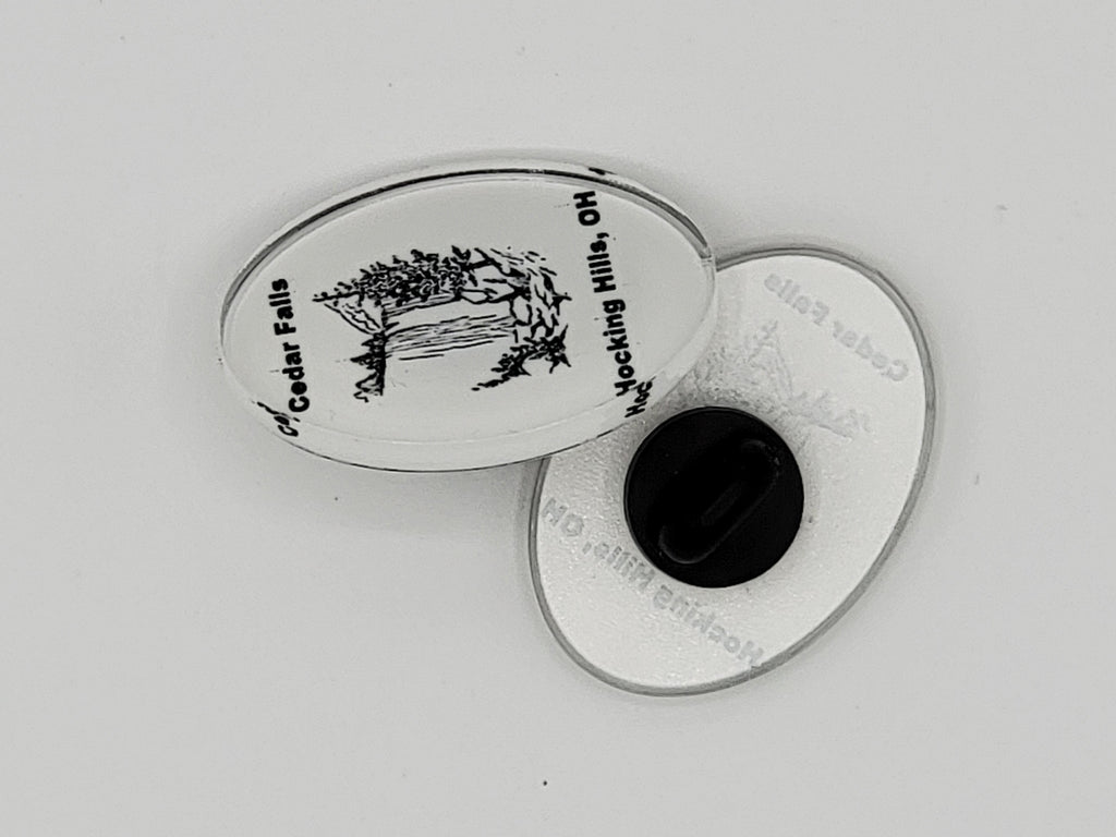 The Hocking Hills Store Cedar Falls oval pin featuring a black and white illustration of a waterfall and trees. Text reads "Cedar Falls Hocking Hills, OH".