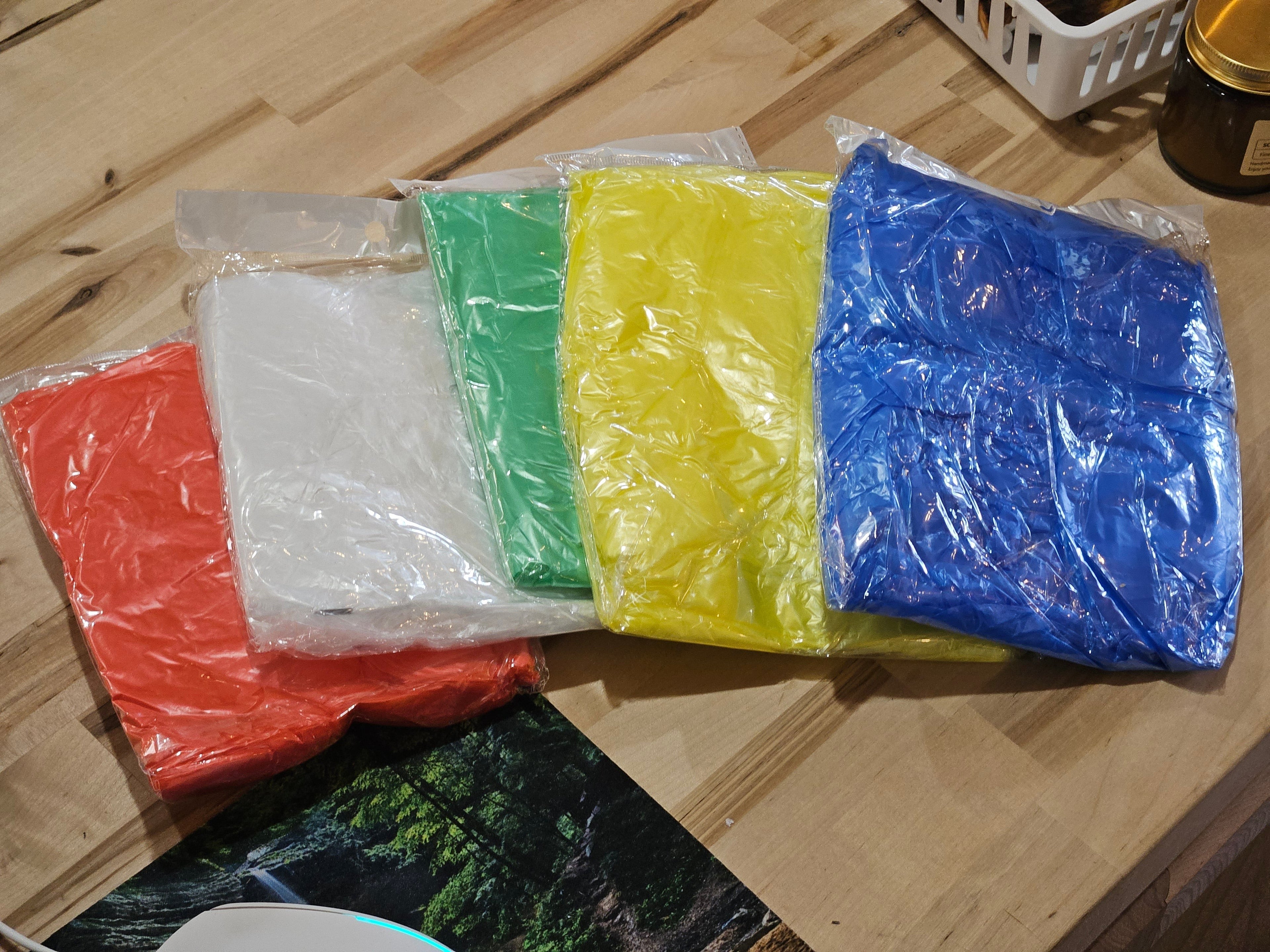 The Hocking Hills Store disposable emergency rain ponchos in red, white, green, yellow, and blue plastic packaging.